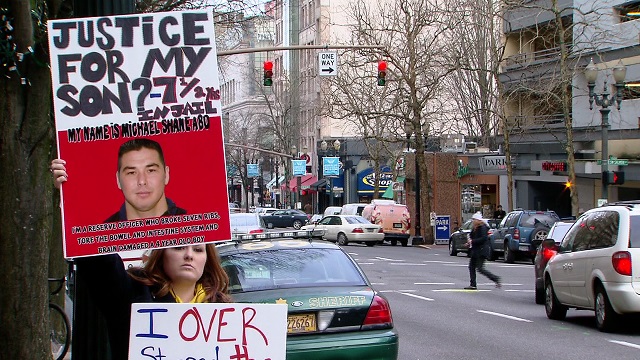 Brandy Robertson holds a protest sign in downtown Portland against the man accused of beating her son, Jan. 12, 2015 (KOIN 6 News)