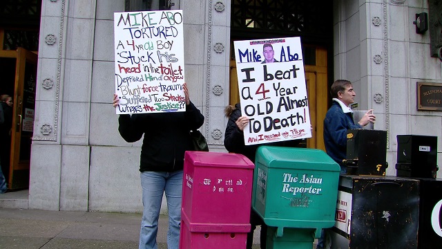 Brandy Robertson's family holds protest signs in downtown Portland against the man accused of beating her son, Jan. 12, 2015 (KOIN 6 News)