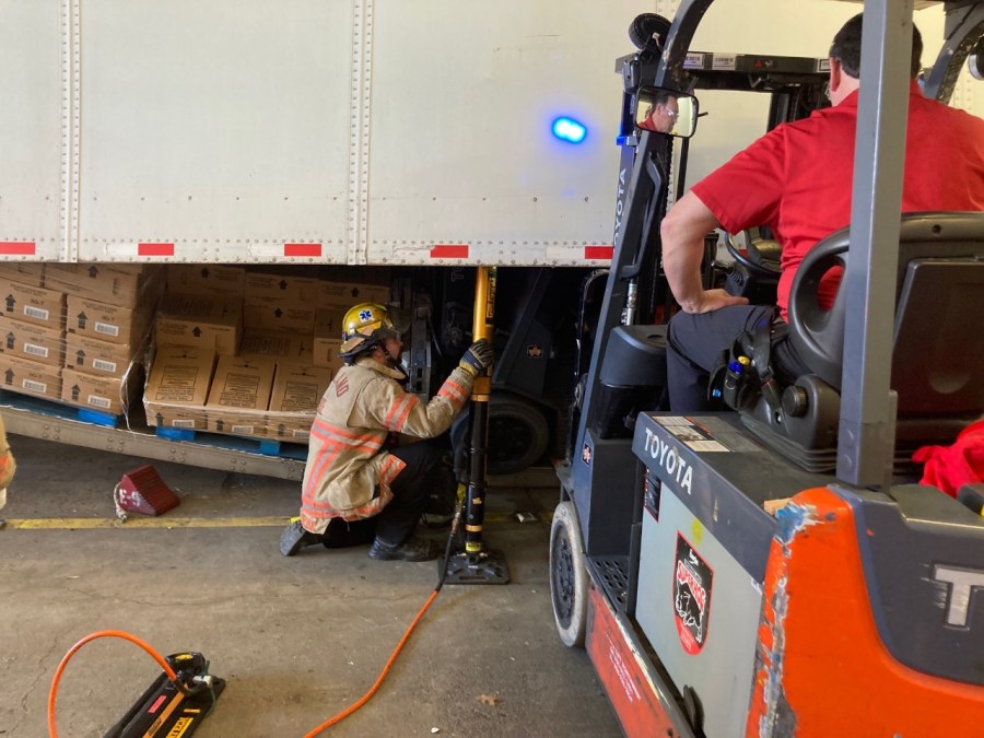 A person's hand was pinned against a semi-trailer after a forklift tipped over at the Coca-Cola plant in Northeast Portland Monday, according to officials.