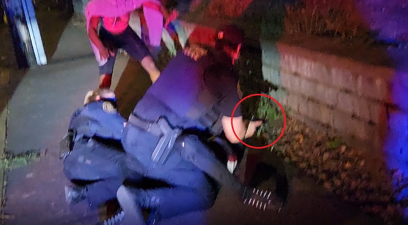 In this screen grab from video, Portland police officers struggle with a suspect and grab his gun (circled) moments before the suspect was shot by police, July 24, 2022 (Courtesy: Oregon Cop Watch)