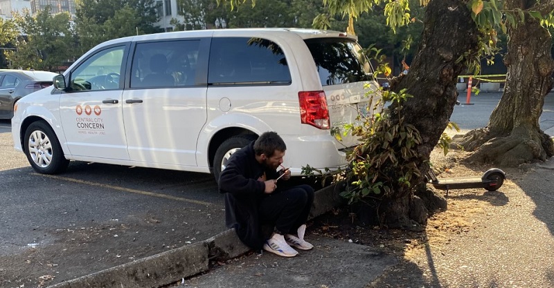 A man sitting in front of a Central City Concern van lights a pipe around NW 4th and Davis in Portland, September 19, 2022 (KOIN)