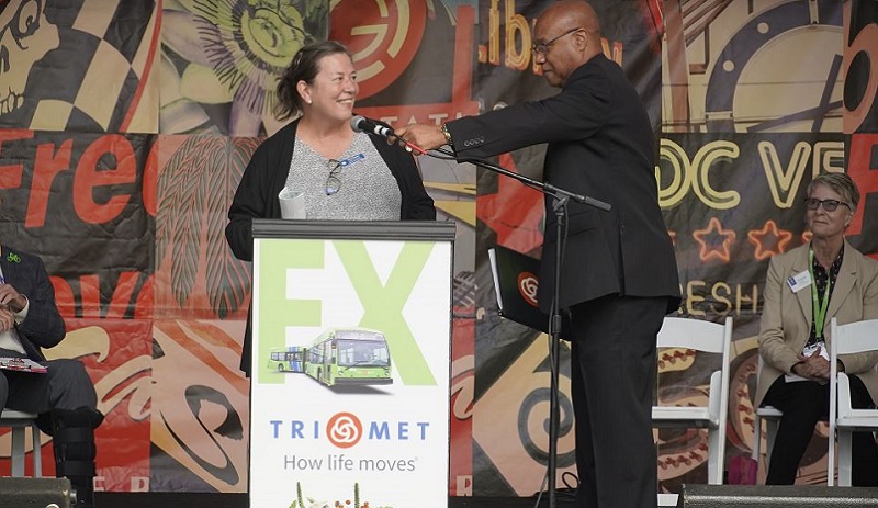 General Manager Sam Desue Jr. adjusts the microphone for FTA Region 10 Administrator, Linda Gherke during TriMet’s FX2-Divison Grand Opening Celebration, September 17, 2022 (TriMet)