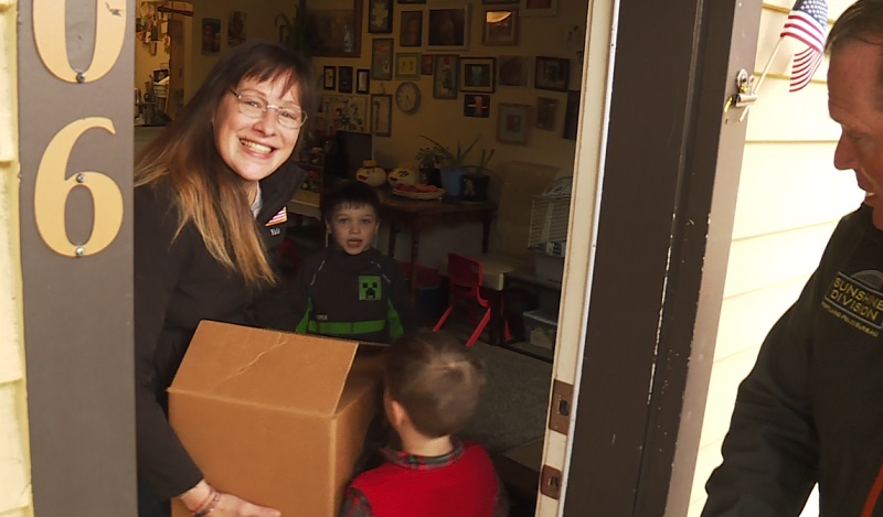 A family smiles broadly after receiving a food delivery from the Sunshine Division in Portland, November 2022 (KOIN)