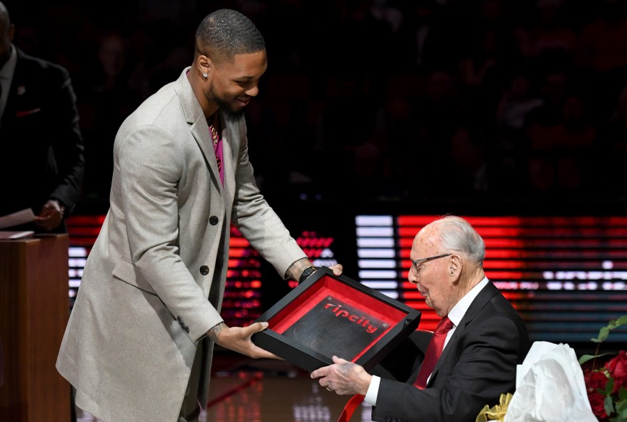 Portland Trail Blazers guard Damian Lillard, left, presents former radio announcer Bill Schonely with a 'Rip City' plaque as he is honored during against the Utah Jazz in Portland, April 10, 2022.  (AP Photo/Steve Dykes)