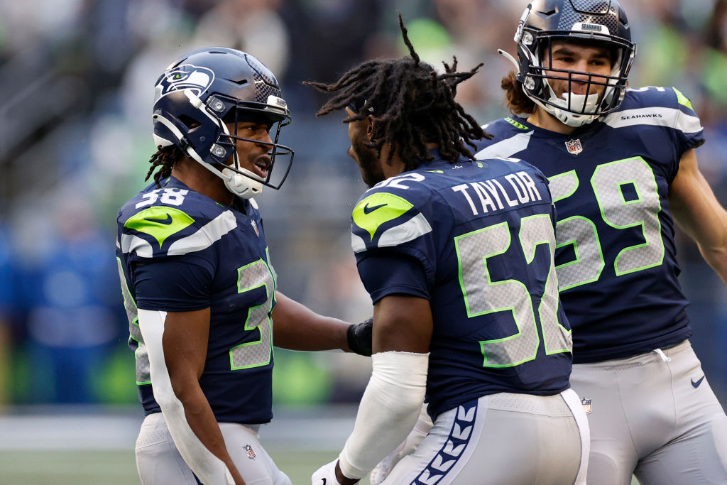 Godwin Igwebuike #38 reacts with Darrell Taylor #52 of the Seattle Seahawks after a play in the first half of the game against the Carolina Panthers at Lumen Field on December 11, 2022 in Seattle, Washington. (Photo by Steph Chambers/Getty Images)