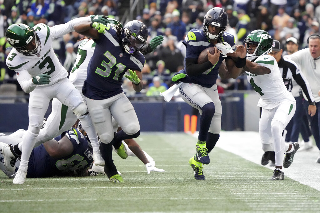 Seattle Seahawks quarterback Geno Smith runs for a first down as New York Jets cornerback D.J. Reed (4) defends during the first half of an NFL football game, Sunday, Jan. 1, 2023, in Seattle. (AP Photo/Ted S. Warren)