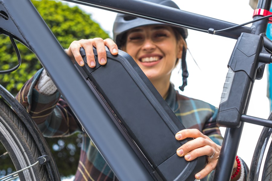 Woman holds an electric bike battery mounted on a frame. (Getty image)