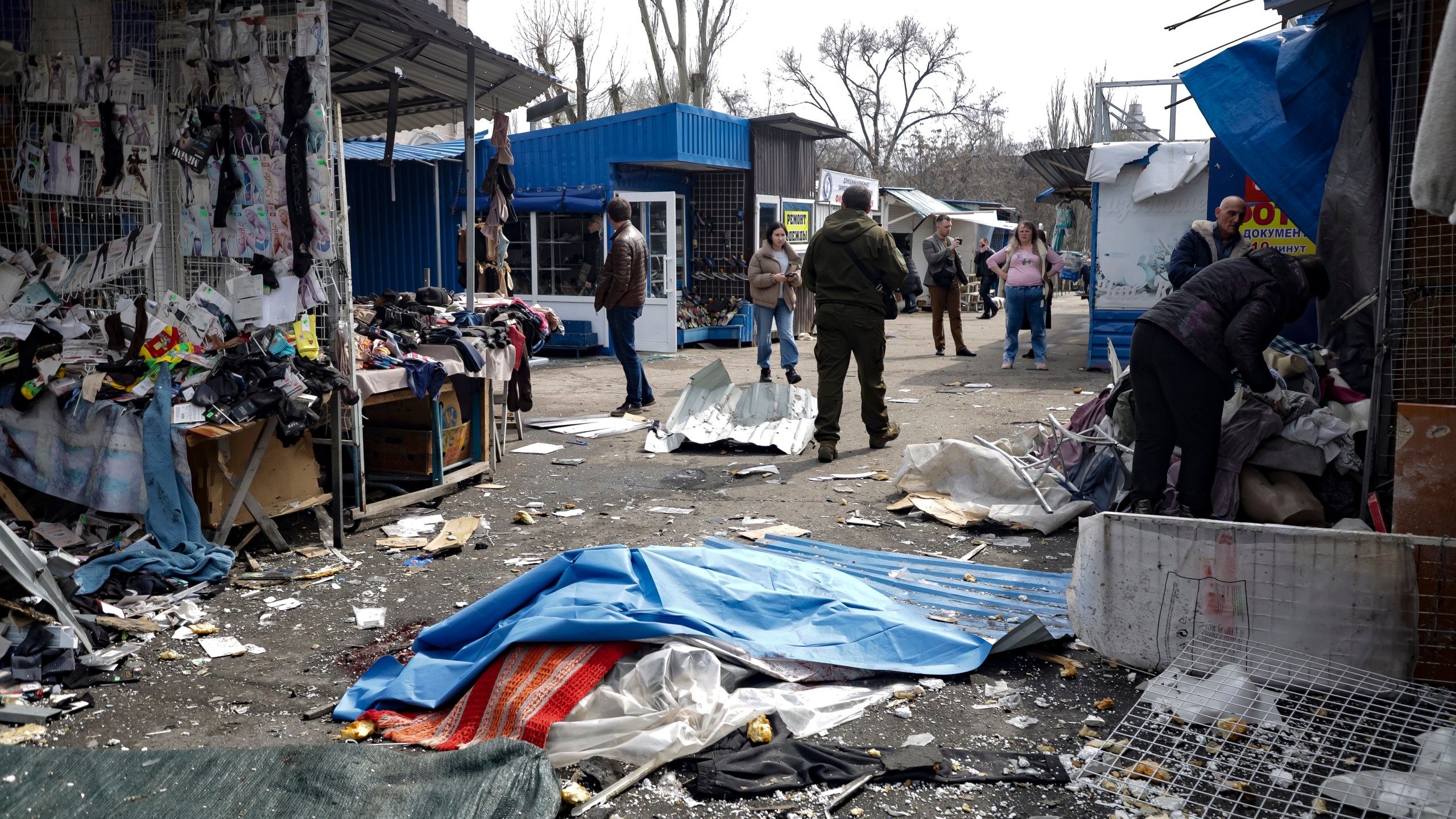 A lifeless body covered by plastic lies on the ground at a street market after the shelling that Russian officials in Donetsk said was conducted by Ukrainian forces, in Donetsk, in Russian-controlled Donetsk region, eastern Ukraine, Friday, April 7, 2023. (AP Photo)