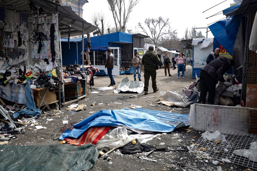 A lifeless body covered by plastic lies on the ground at a street market after the shelling that Russian officials in Donetsk said was conducted by Ukrainian forces, in Donetsk, in Russian-controlled Donetsk region, eastern Ukraine, Friday, April 7, 2023. (AP Photo)