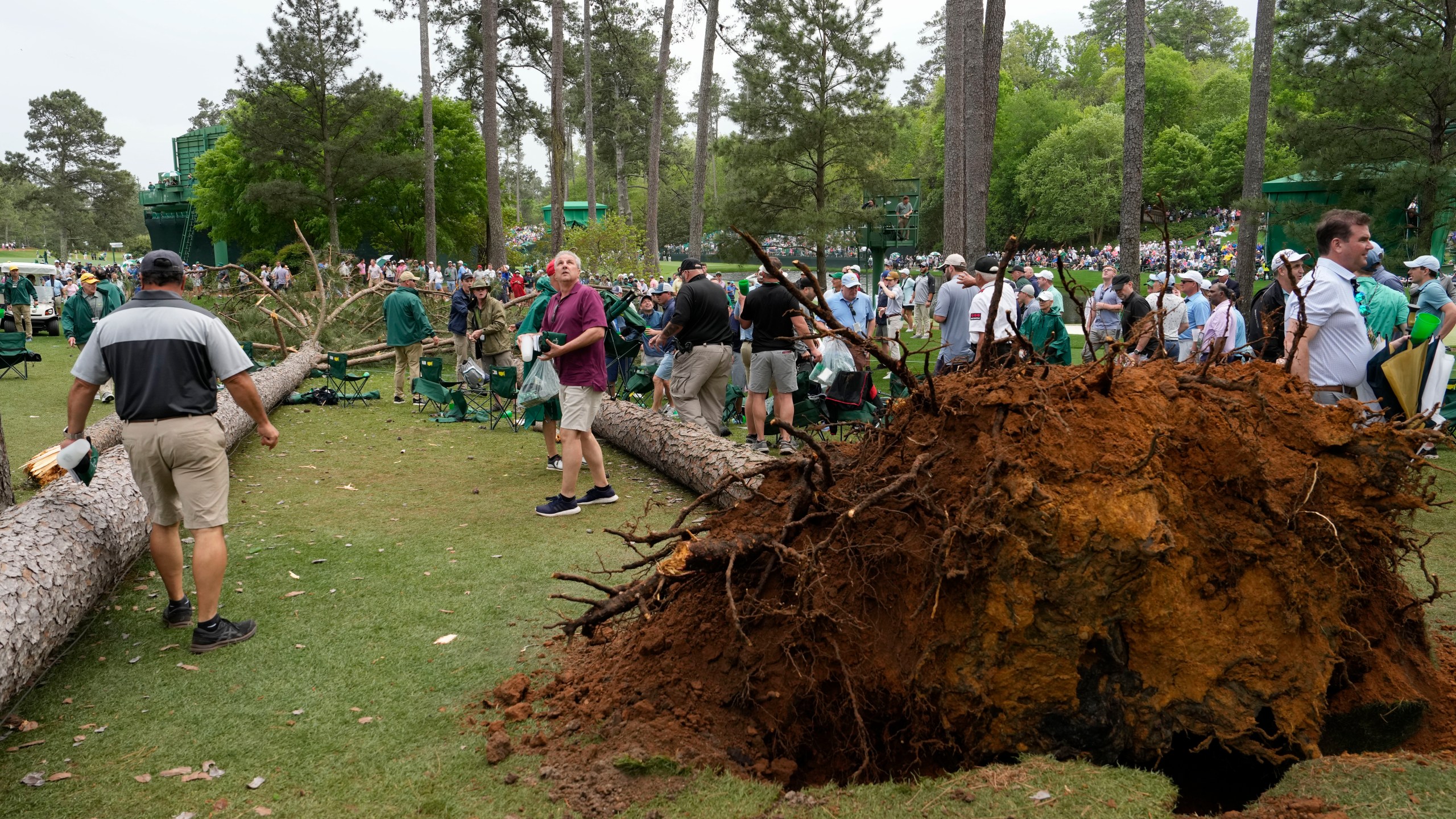 Patrons move away from two trees that blew over on the 17th hole during the second round of the Masters golf tournament at Augusta National Golf Club on Friday, April 7, 2023, in Augusta, Ga. (AP Photo/Mark Baker)