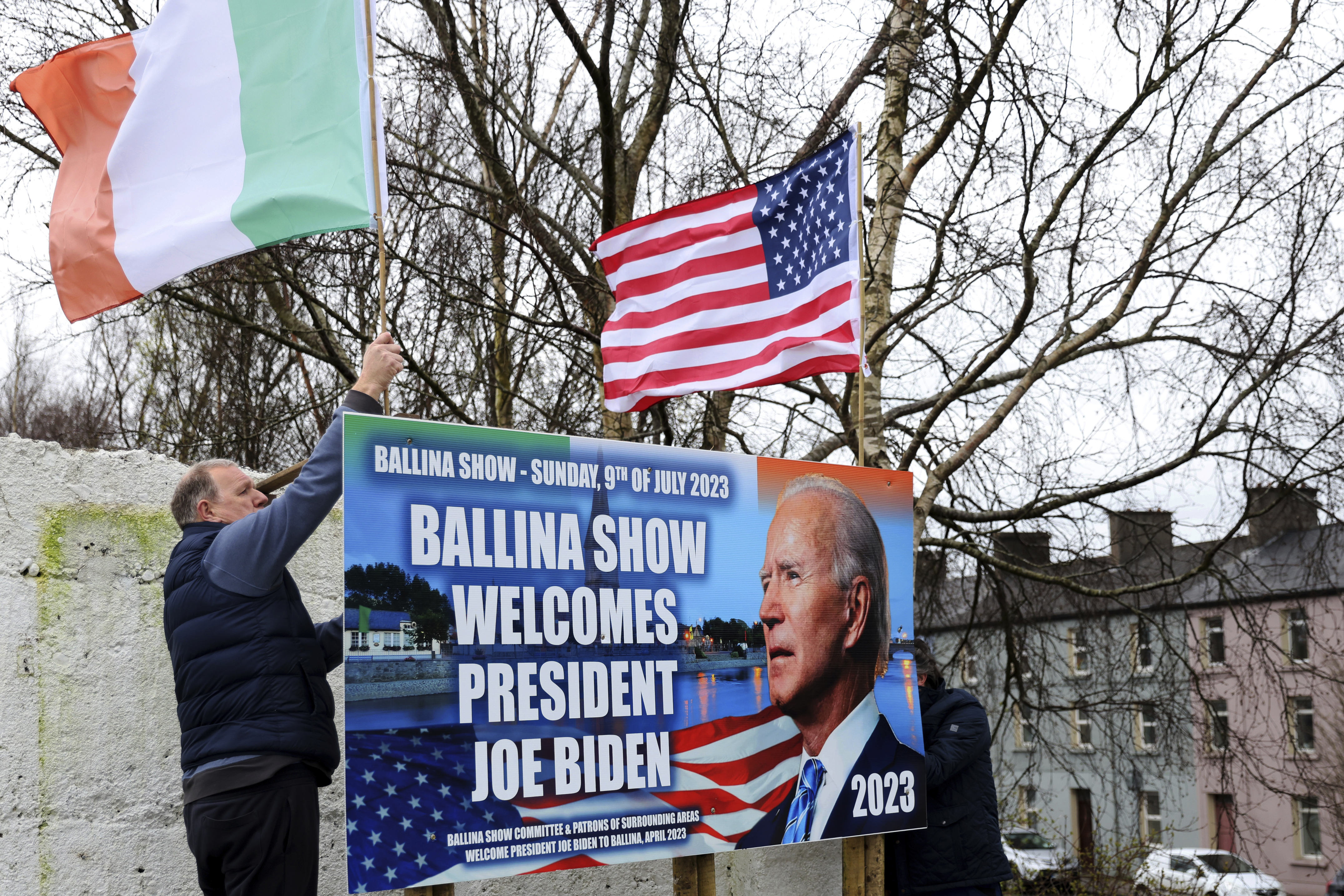 Ray Clarke, left, and Eddie Ruane put up flags in Ballina, Ireland, Tuesday, April, 4, 2023. Excitement is building in Ballina, a small Irish town that was home to some of President Joe Biden's ancestors. Biden is scheduled to visit the town next week, part of a four-day trip to Ireland and neighboring Northern Ireland. (AP Photo/Peter Morrison)