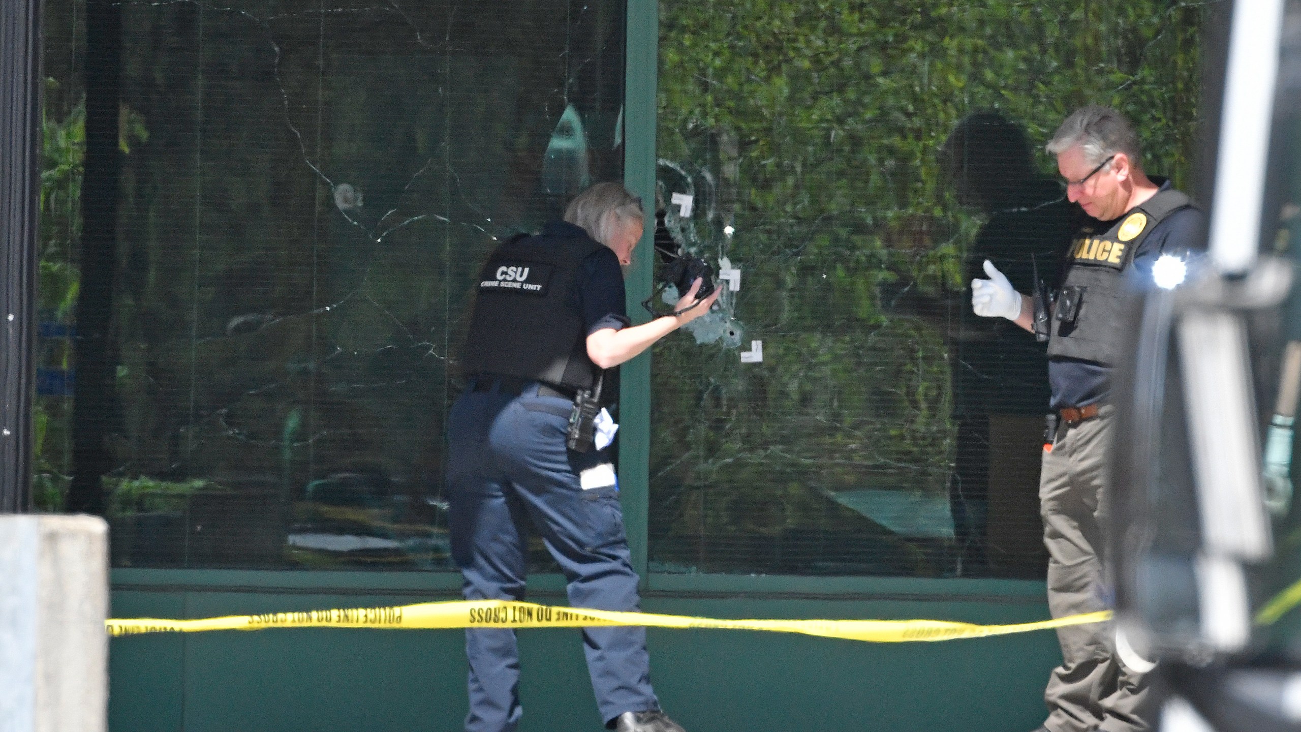 A Louisville Metro Police technician photographs bullet holes in the front glass of the Old National Bank building in Louisville, Ky., Monday, April 10, 2023. A shooting at the bank killed and wounded several people police said. The suspected shooter was also dead. (AP Photo/Timothy D. Easley)