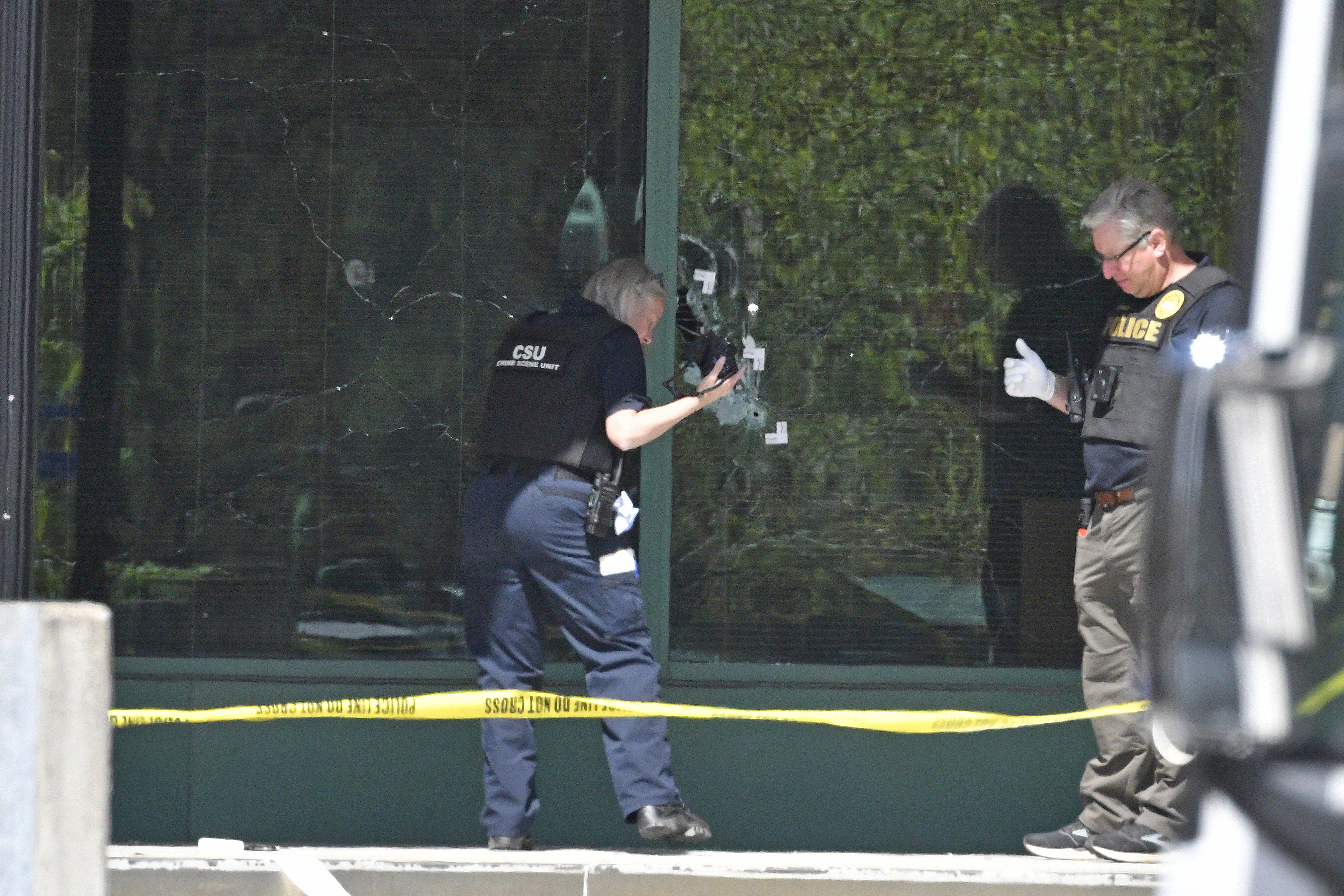 A Louisville Metro Police technician photographs bullet holes in the front glass of the Old National Bank building in Louisville, Ky., Monday, April 10, 2023. A shooting at the bank killed and wounded several people police said. The suspected shooter was also dead. (AP Photo/Timothy D. Easley)