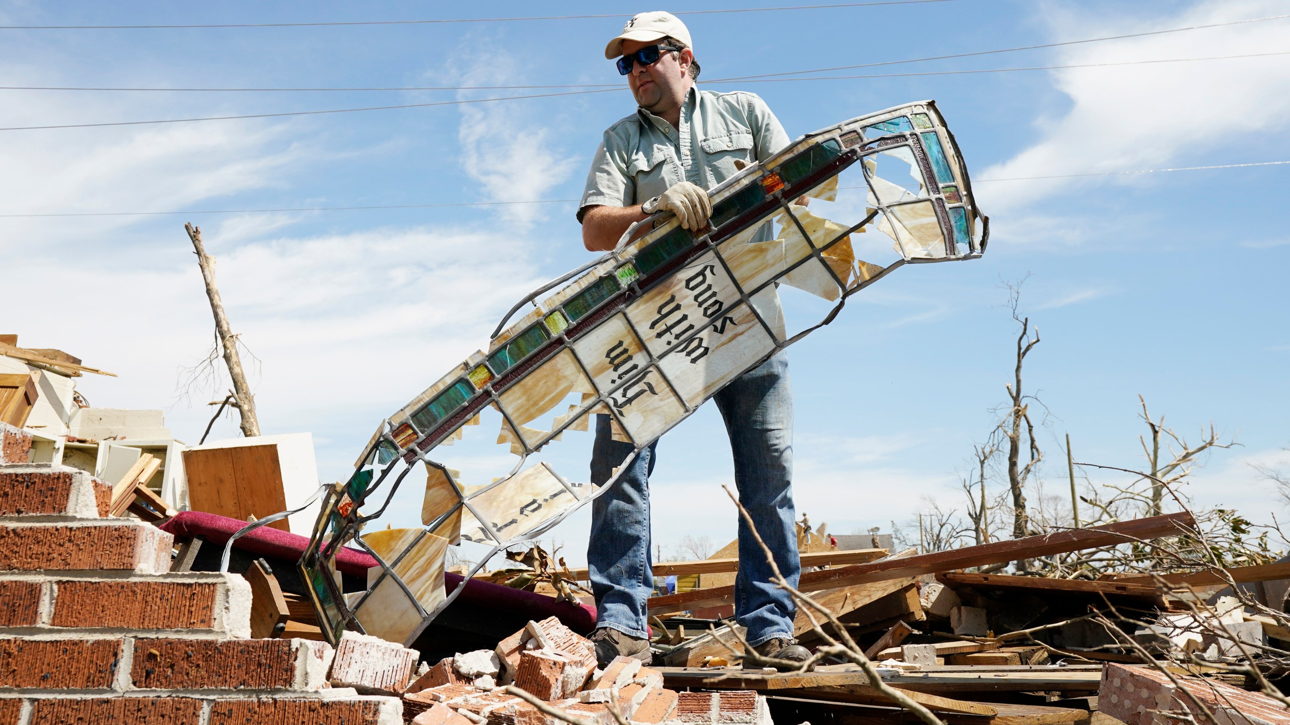 Charlie Weissinger carefully removes a stained glass window frame as he searches for his family's stained glass window in the rubble left from a March 24 tornado, that hit The Chapel of The Cross Episcopal Church in Rolling Fork, Miss., on March 29, 2023. The Weissinger family roots run deep in the 99-year old church and largely farming community and he expects his family will join members in rebuilding the church and repairing the family home which was damaged by the killer tornado. (AP Photo/Rogelio V. Solis)