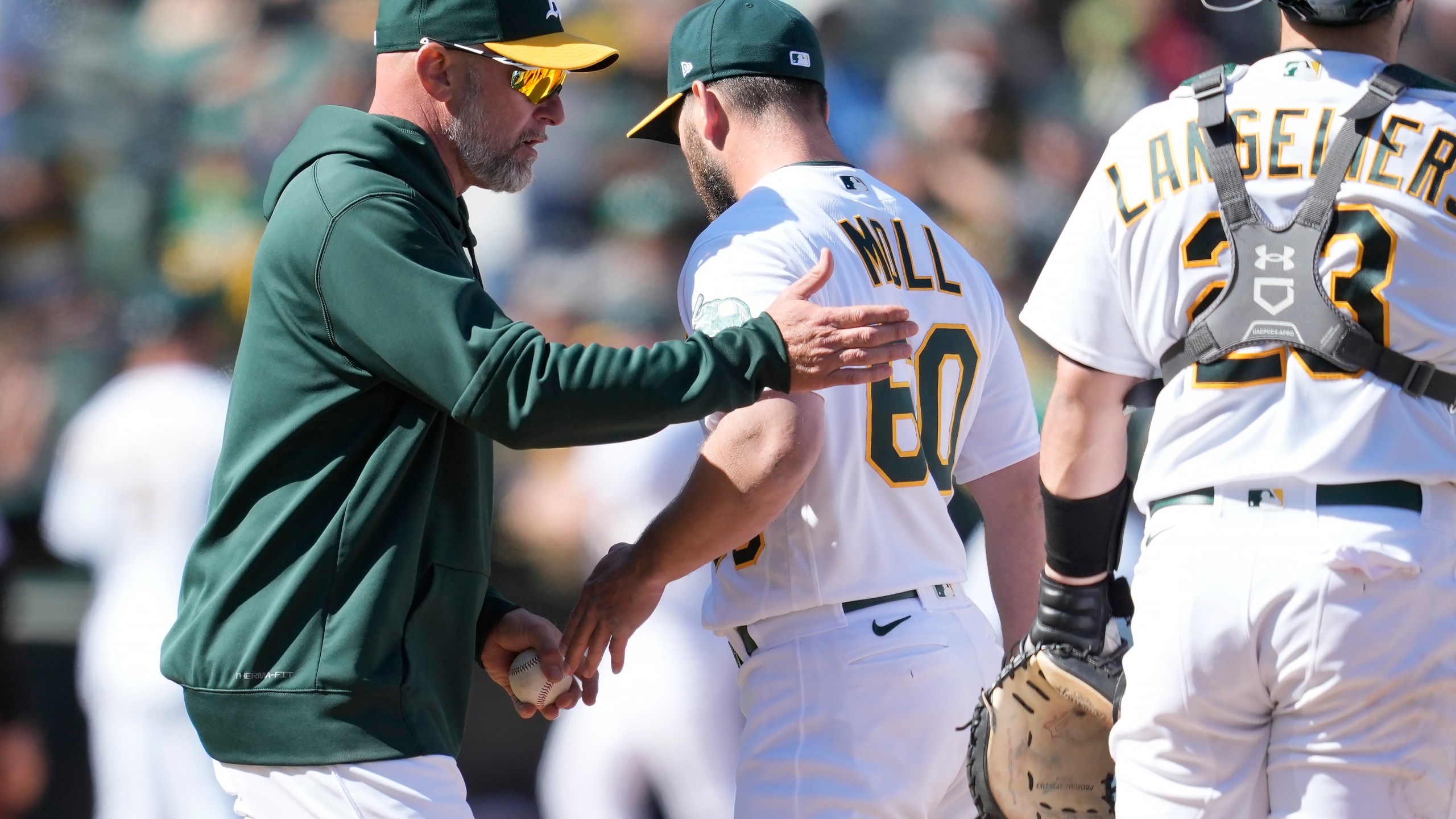 Oakland Athletics manager Mark Kotsay, left, makes a pitching change as he relieves pitcher Sam Moll (60) during the 10th inning of a baseball game against the New York Mets in Oakland, Calif., Sunday, April 16, 2023. (AP Photo/Jeff Chiu)