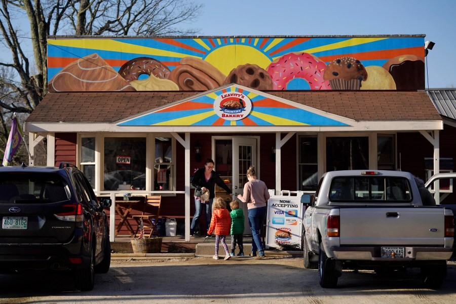 A customer holds the door for a family arriving at Leavitt's Country Bakery, Thursday, April 13, 2023, in Conway, N.H. The large painting of pastries created by students and displayed over the bakery is at the center of a legal battle pitting a zoning ordinance against freedom-of-speech rights. (AP Photo/Robert F. Bukaty)