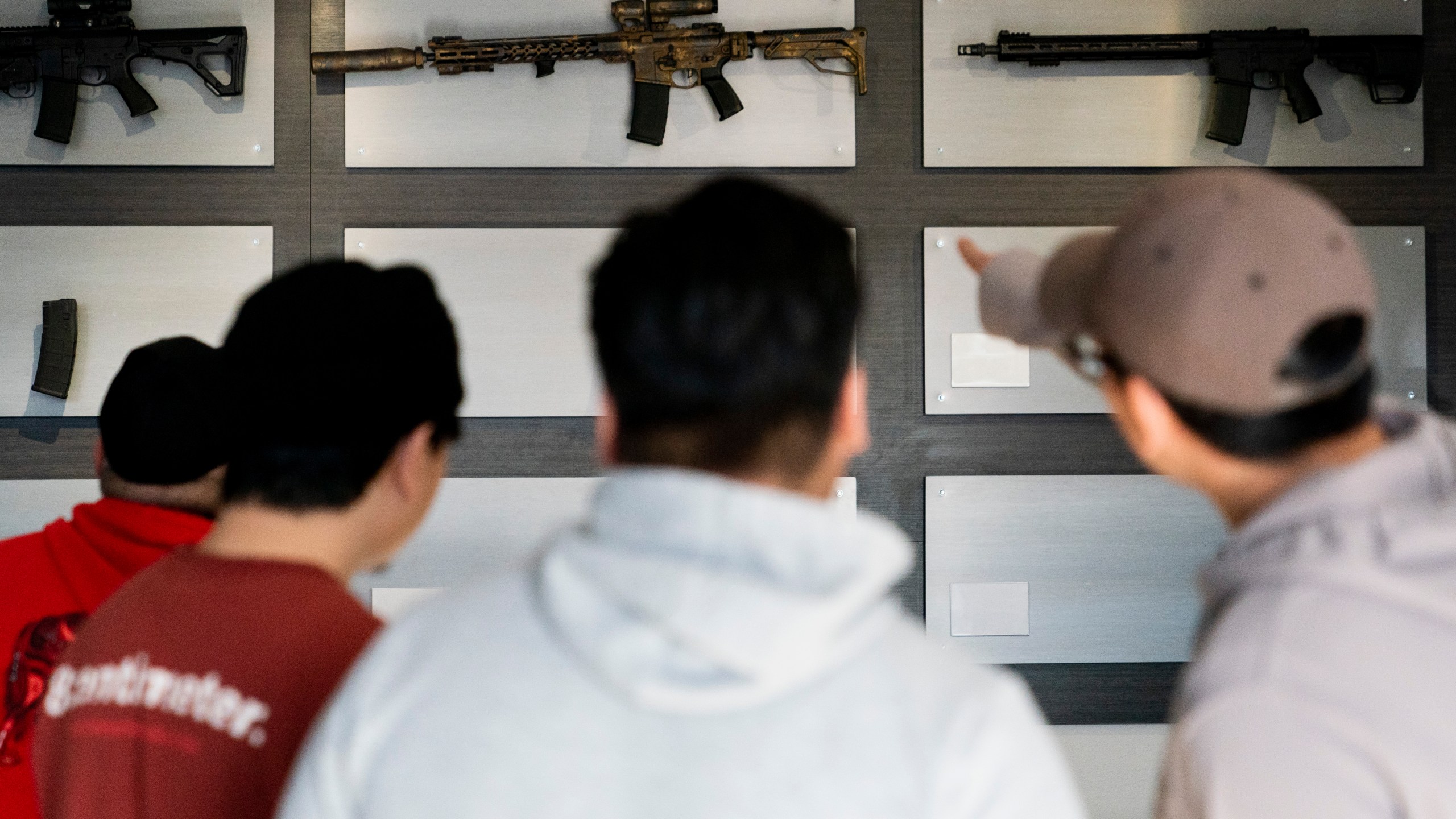 Customers look at AR-15-style rifles on a mostly empty display wall at Rainier Arms Friday, April 14, 2023, in Auburn, Wash. as stock dwindles before potential legislation that would ban future sale of the weapons in the state. House Bill 1240 would ban the future sale, manufacture and import of assault-style semi-automatic weapons to Washington State and would go into immediate effect after being signed by Gov. Jay Inslee. (AP Photo/Lindsey Wasson)