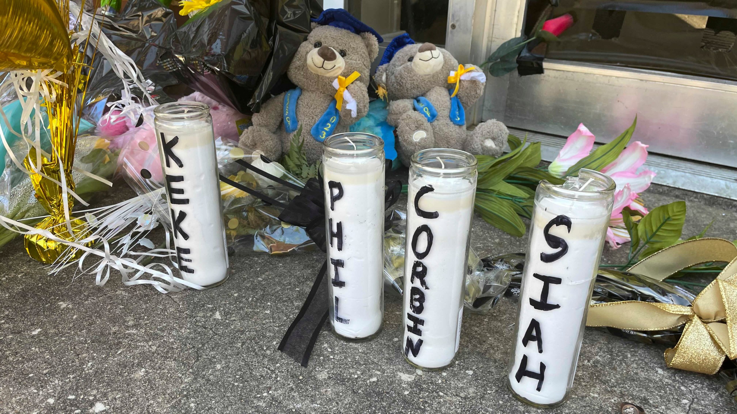 Candles with the names of the four young people killed in a shooting and teddy bears dressed in graduation caps sit outside the Mahogany Masterpiece dance studio on Wednesday, April 19, 2023, in Dadeville, Ala. Two teenagers have been arrested and charged with murder in connection with the shooting at a Sweet Sixteen birthday party, Alabama investigators announced Wednesday. (AP Photo/Kimberly Chandler)