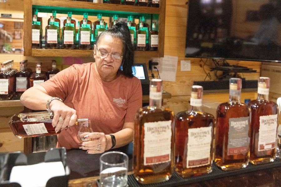 Bartender June Davis pours drinks inside the Hochatown Distilling Co. bar in Broken Bow, Okla. on Thursday, April 20, 2023. The growing optimism of McCurtain County's tourism boom over the last two decades took a gut punch last week when the local newspaper identified several county officials, including the sheriff and a county commissioner, who were caught on tape discussing killing journalists and lynching Black people. (AP Photo/Alonzo Adams)