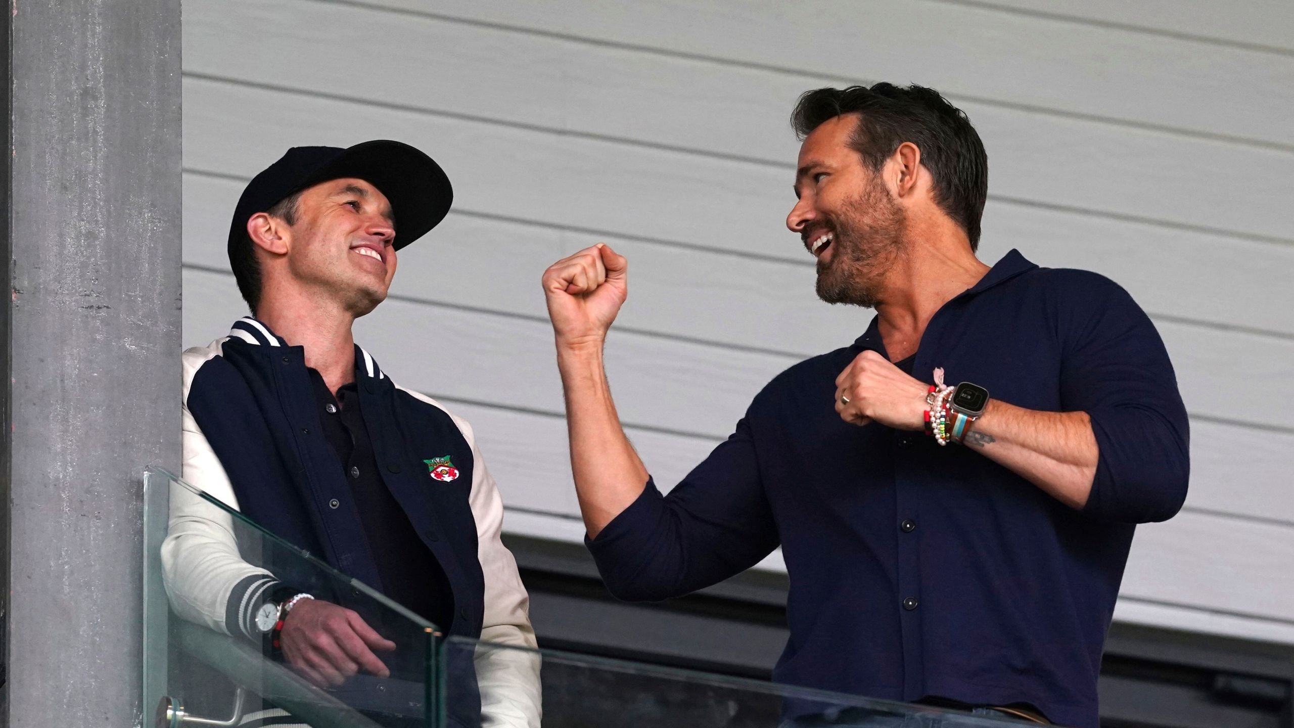 Wrexham co-owners Rob McElhenney, left, and Ryan Reynolds in the stands during the National League soccer match between Wrexham and Boreham Wood at The Racecourse Ground, in Wrexham, Wales, Saturday April 22, 2023. (Martin Rickett/PA via AP)