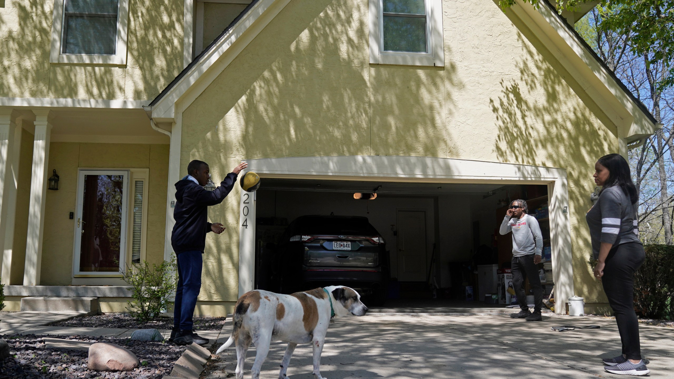 Kia Breaux, right, plays ball with her sons Jaden, 14, left, and John, 17, in front of their home in Kansas City, Mo., Friday, April 21, 2023. The recent shooting of Black teenager Ralph Yarl by an 84-year-old white man when Yarl mistakenly went to the wrong address in a nearby neighborhood, has shaken many Black residents in the predominantly white region of the city. (AP Photo/Charlie Riedel)