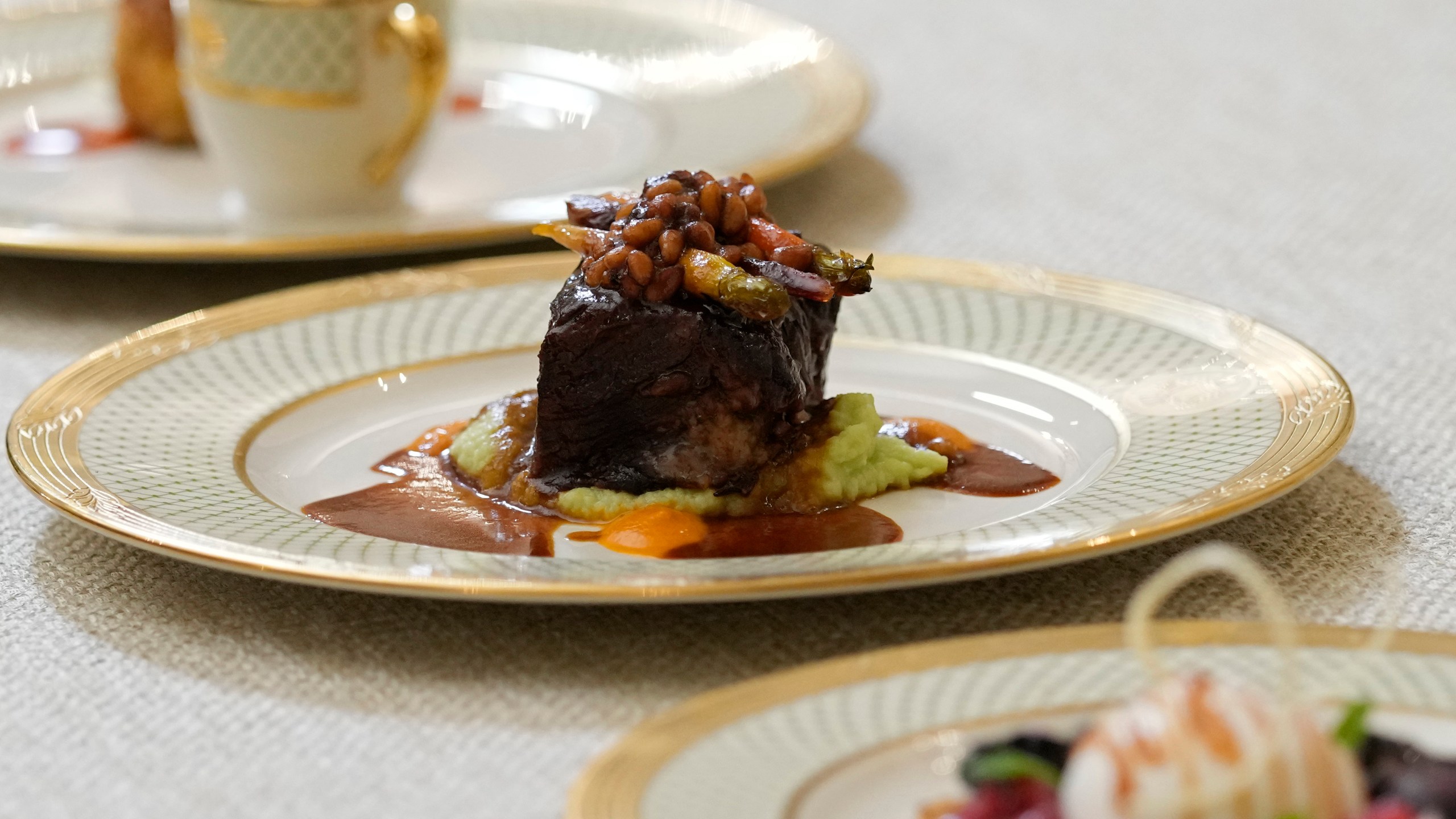 Dishes are displayed during a media preview, Monday, April 24, 2023, in advance of Wednesday's State Dinner with South Korea's President Yoon Suk Yeol at the White House in Washington. The dish in the center is a braised beef short rib with butter bean grits, sorghum-glazed carrots and pine nuts. (AP Photo/Susan Walsh)