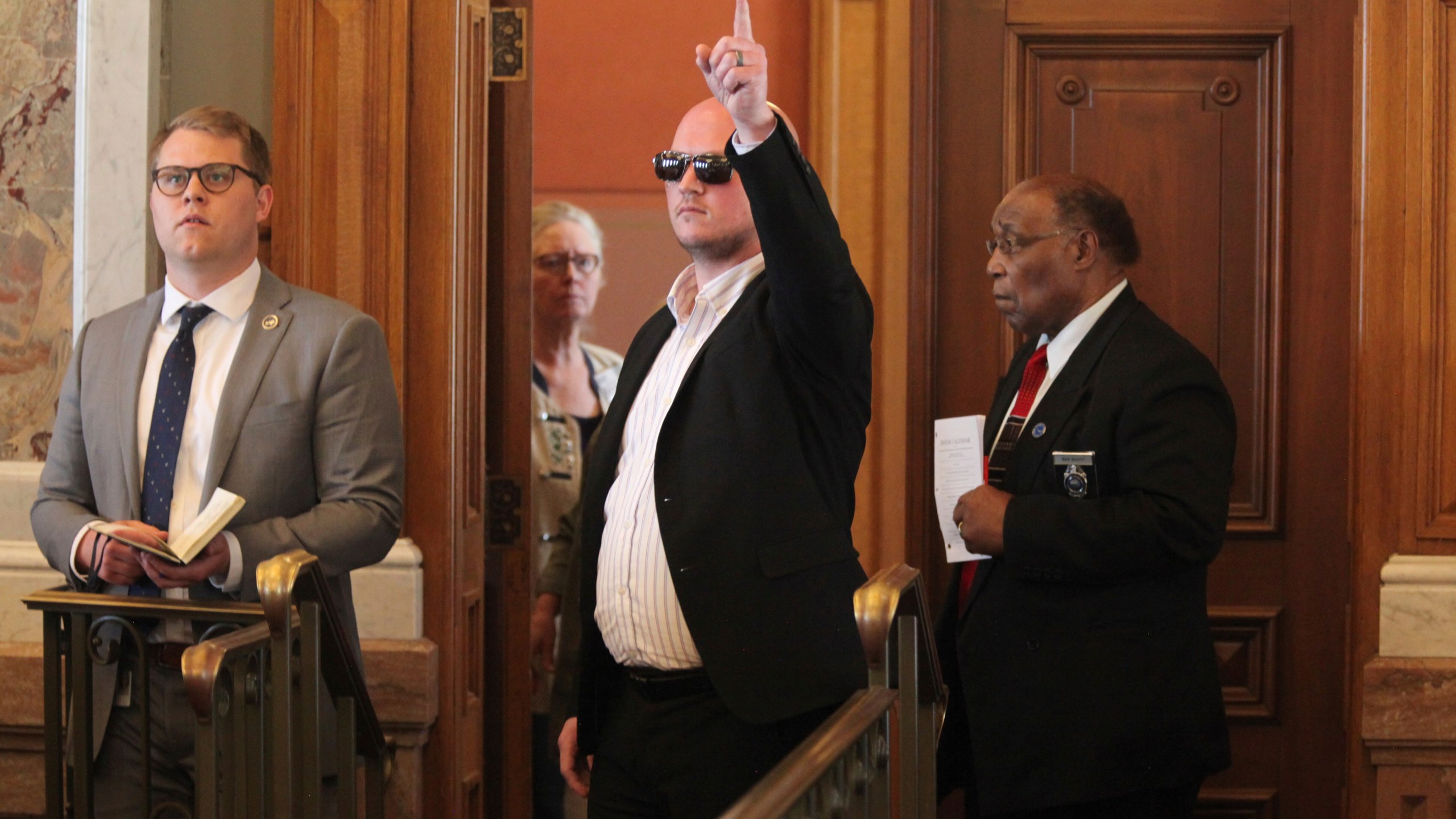 Kansas state Rep. Adam Thomas, R-Olathe, signals his vote in favor of overriding a veto from Gov. Laura Kelly of an anti-abortion bill from the back of the chamber, Wednesday, April 26, 2023, at the Statehouse in Topeka, Kansas. Thomas spent only brief moments in the chamber because a line drive hit him directly in the face while he was pitching during a recent softball game, resulting in serious injuries. (AP Photo/John Hanna)