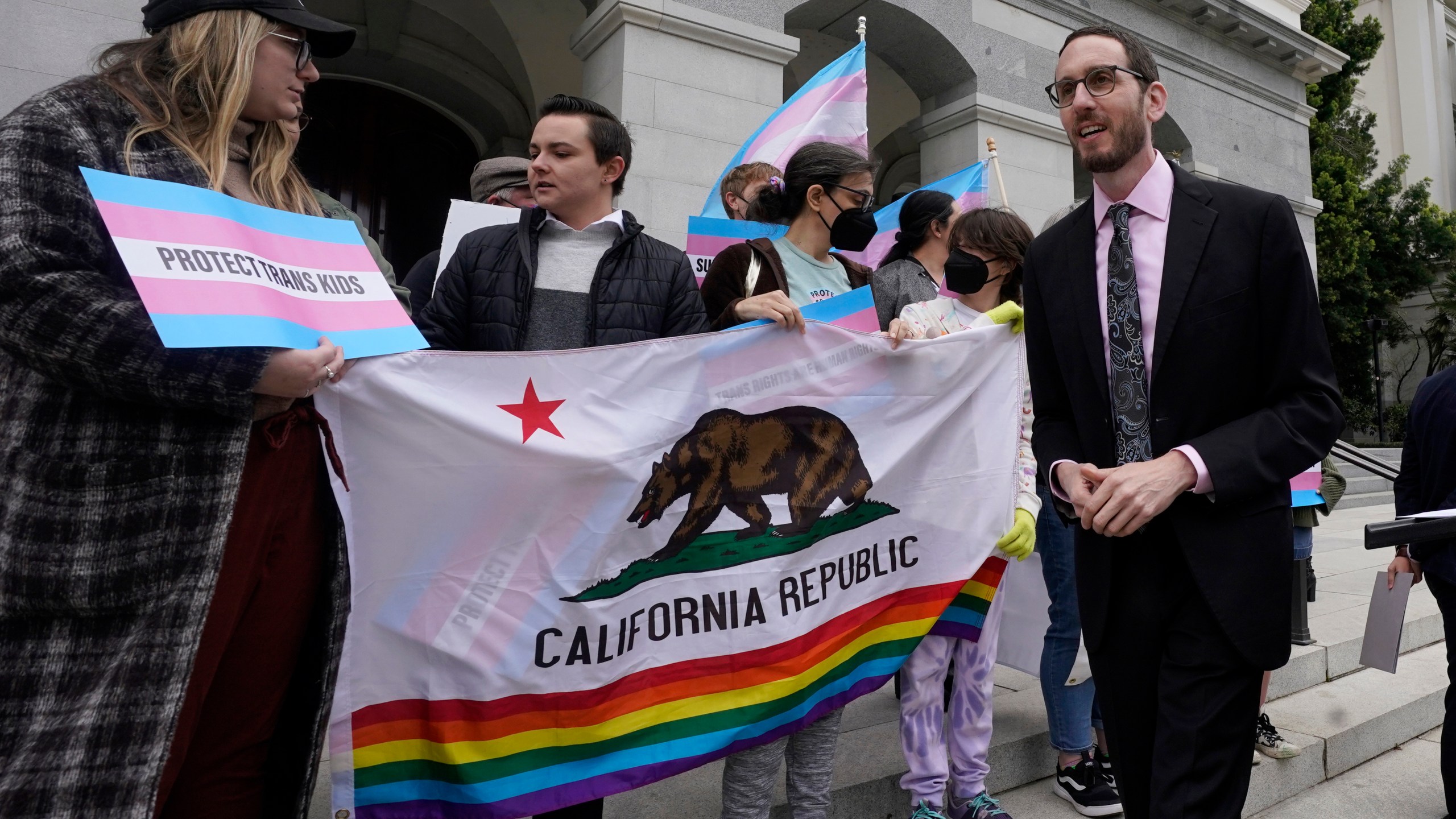 FILE - State Sen. Scott Wiener, D-San Francisco, right, prepares to announce his proposed measure to provide legal refuge to displaced transgender youth and their families during a news conference in Sacramento, Calif., on March 17, 2022. San Francisco is repealing a ban on city-funded travel to 30 states that it says restrict abortion, voting and LGBTQ rights after determining the boycott is doing more harm than good. Wiener, a former supervisor-turned-state senator who authored the original ban, agreed that the measure hadn't produced the intended results. (AP Photo/Rich Pedroncelli, File)