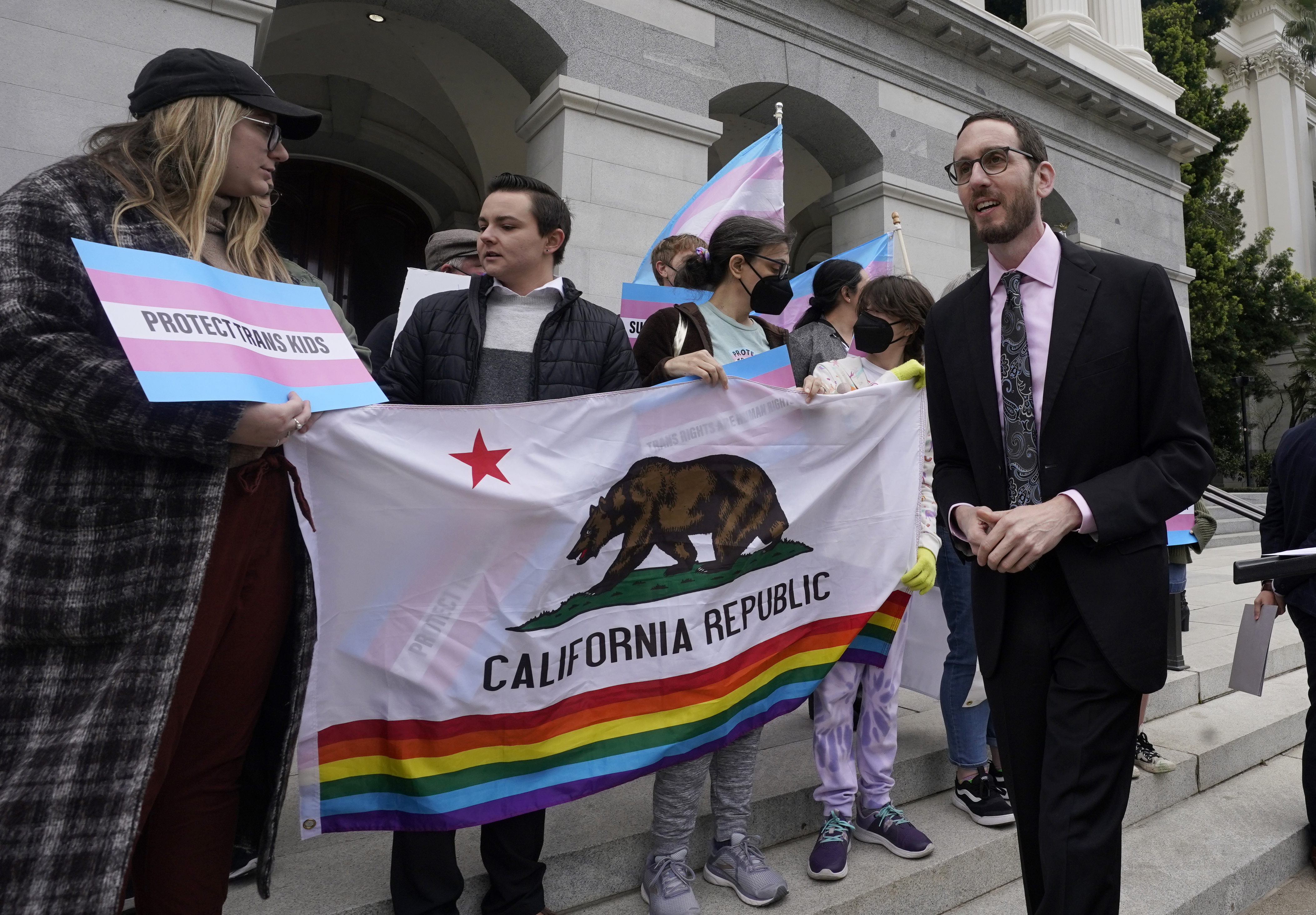 FILE - State Sen. Scott Wiener, D-San Francisco, right, prepares to announce his proposed measure to provide legal refuge to displaced transgender youth and their families during a news conference in Sacramento, Calif., on March 17, 2022. San Francisco is repealing a ban on city-funded travel to 30 states that it says restrict abortion, voting and LGBTQ rights after determining the boycott is doing more harm than good. Wiener, a former supervisor-turned-state senator who authored the original ban, agreed that the measure hadn't produced the intended results. (AP Photo/Rich Pedroncelli, File)