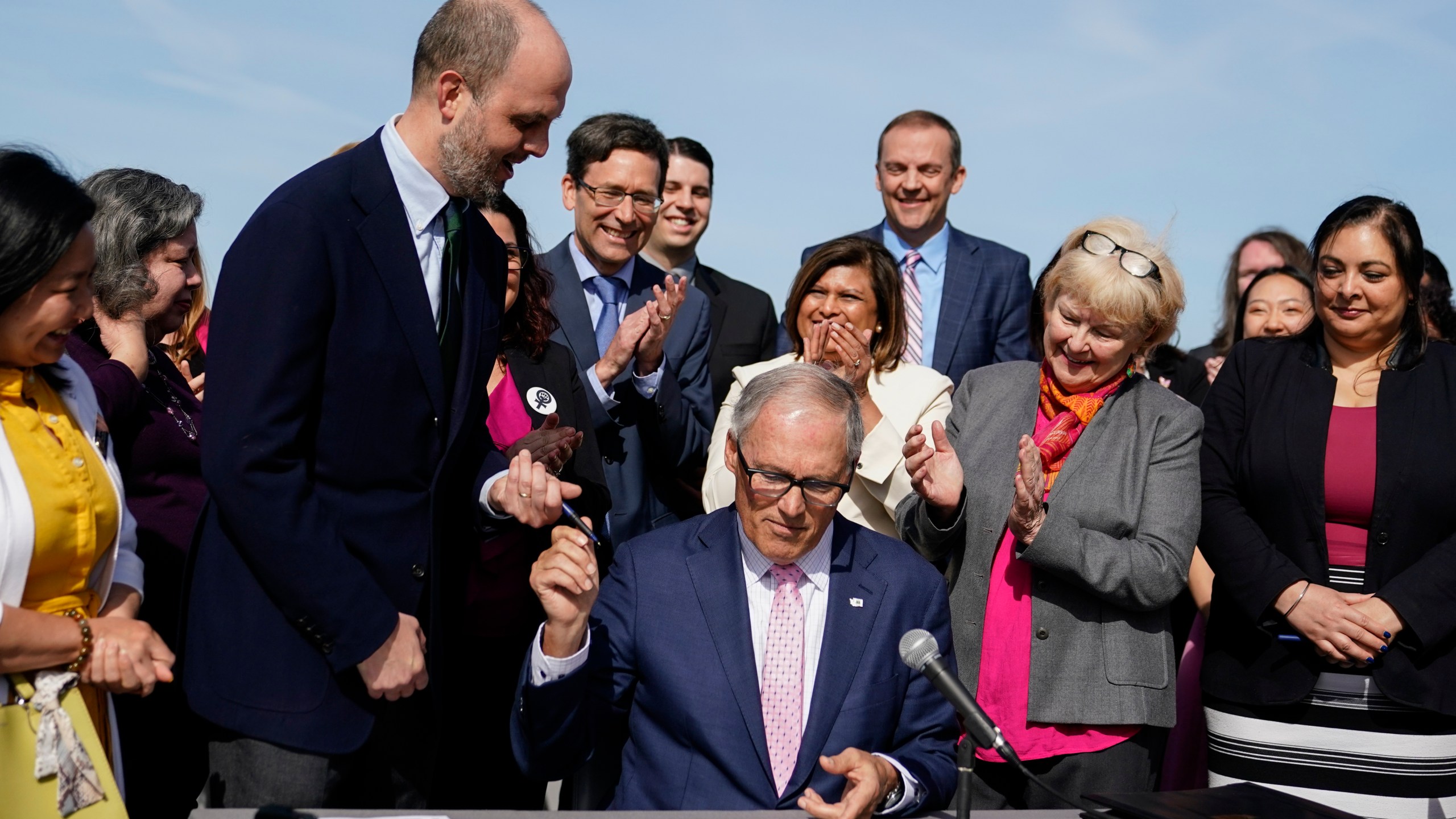 Washington Gov. Jay Inslee hands a pen to Rep. Drew Hansen, D-Bainbridge Island, left, after signing House Bill 1469, which shields abortion and gender-affirming care patients and providers from prosecution by out-of-state authorities and prevents cooperation with investigations, Thursday, April 27, 2023, at the University of Washington's Hans Rosling Center for Population Health in Seattle. (AP Photo/Lindsey Wasson)