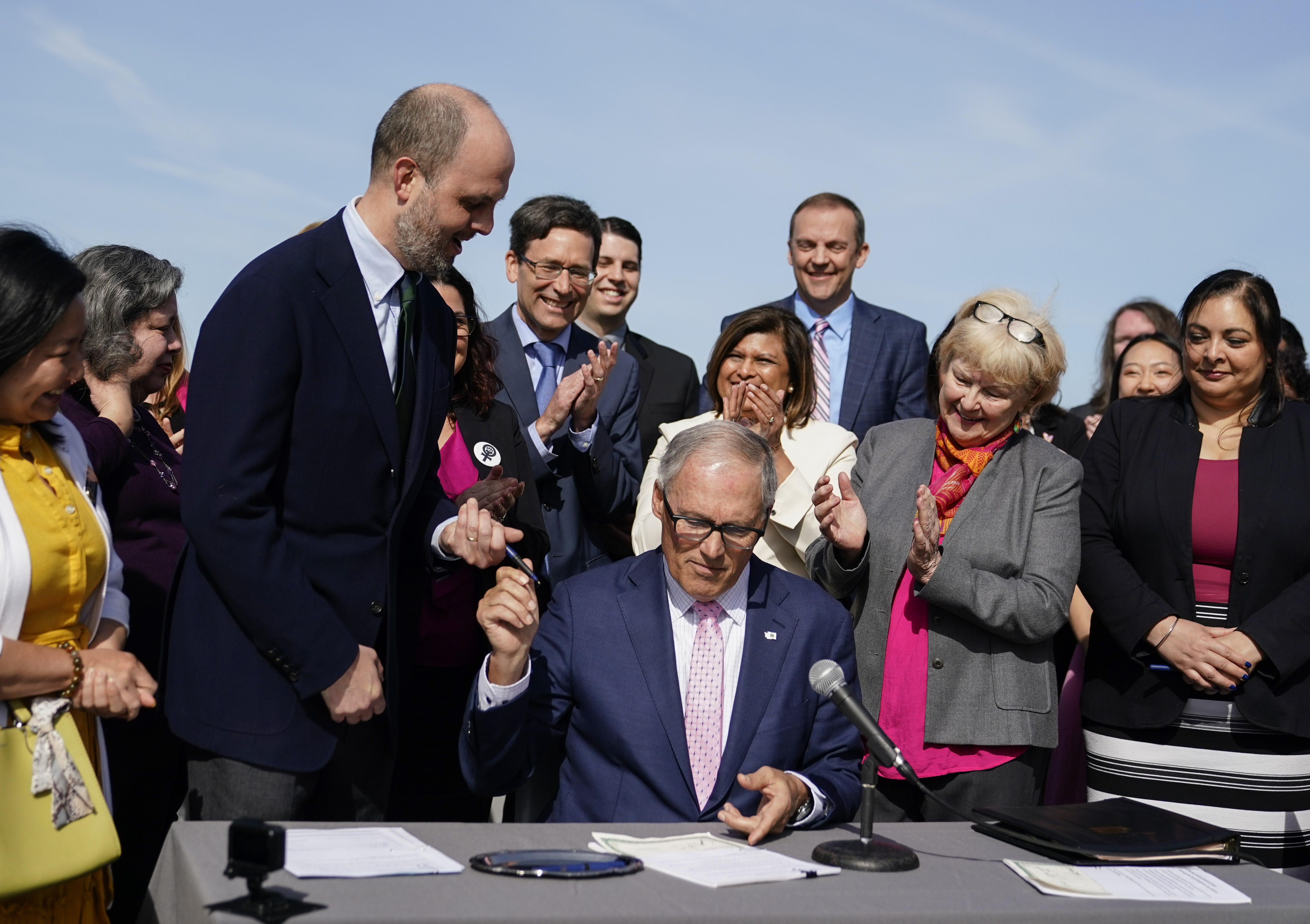 Washington Gov. Jay Inslee hands a pen to Rep. Drew Hansen, D-Bainbridge Island, left, after signing House Bill 1469, which shields abortion and gender-affirming care patients and providers from prosecution by out-of-state authorities and prevents cooperation with investigations, Thursday, April 27, 2023, at the University of Washington's Hans Rosling Center for Population Health in Seattle. (AP Photo/Lindsey Wasson)