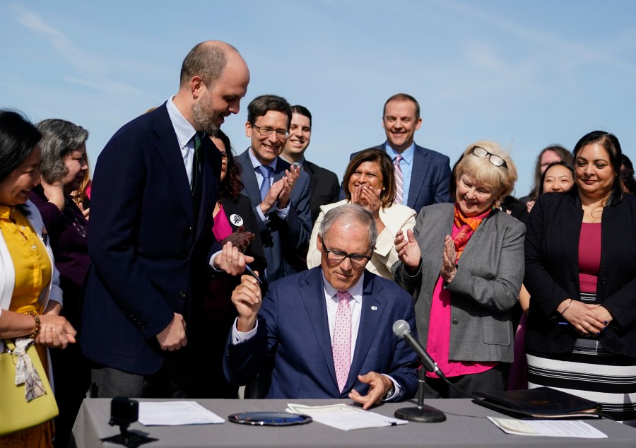 Washington Gov. Jay Inslee hands a pen to Rep. Drew Hansen, D-Bainbridge Island, left, after signing House Bill 1469, which shields abortion and gender-affirming care patients and providers from prosecution by out-of-state authorities and prevents cooperation with investigations, Thursday, April 27, 2023, at the University of Washington's Hans Rosling Center for Population Health in Seattle. (AP Photo/Lindsey Wasson)