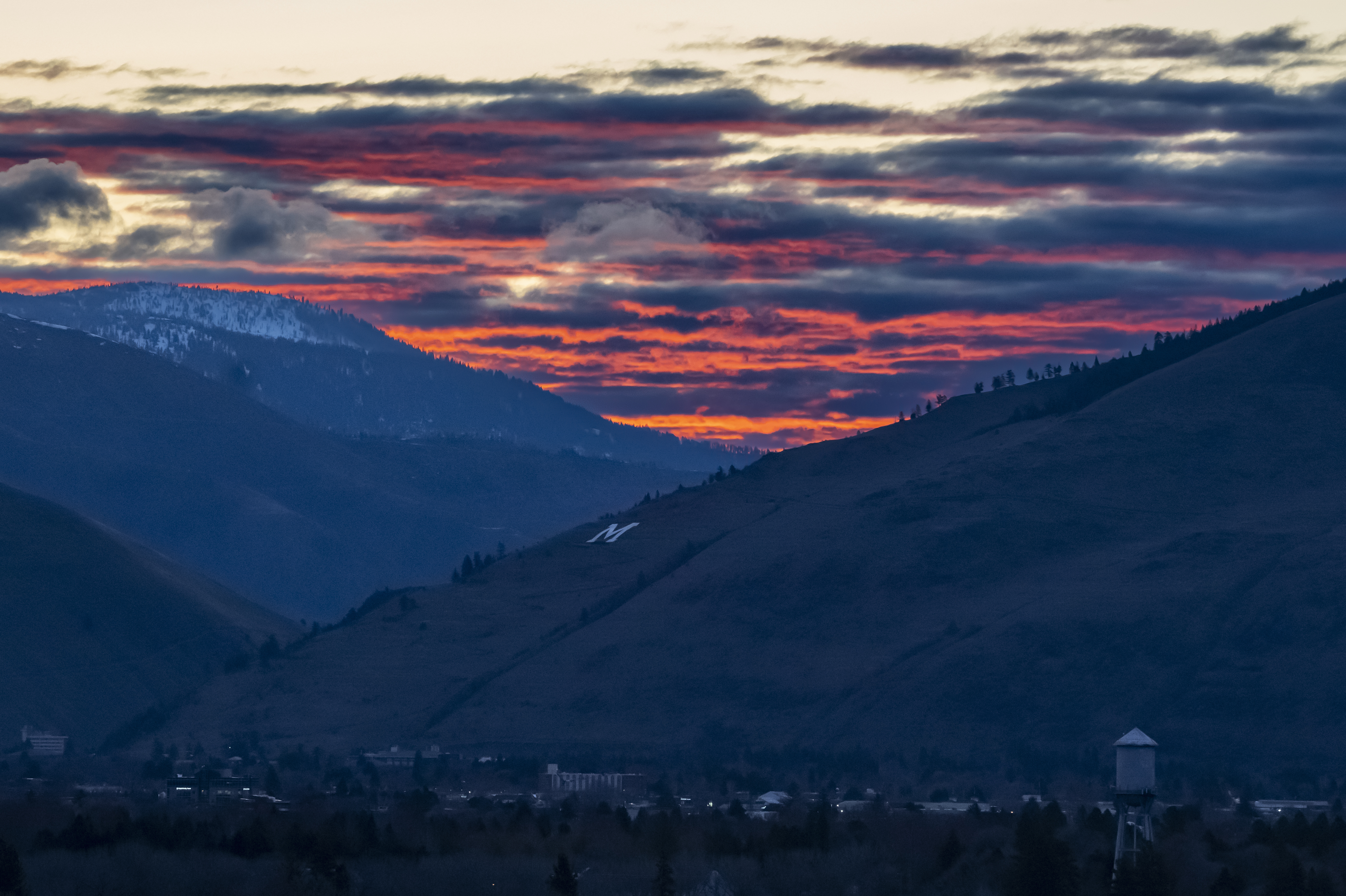 The sun rises beyond Mount Sentinel and downtown Missoula, Mont., Tuesday, April 25, 2023. It was little surprise that Missoula, a college town where pride flags are a common sight, sent Zooey Zephyr to the state legislature. Zephyr, the first openly transgender legislator in Montana’s history, was barred last week from speaking on the floor of the legislature by the Republican majority. (AP Photo/Tommy Martino)