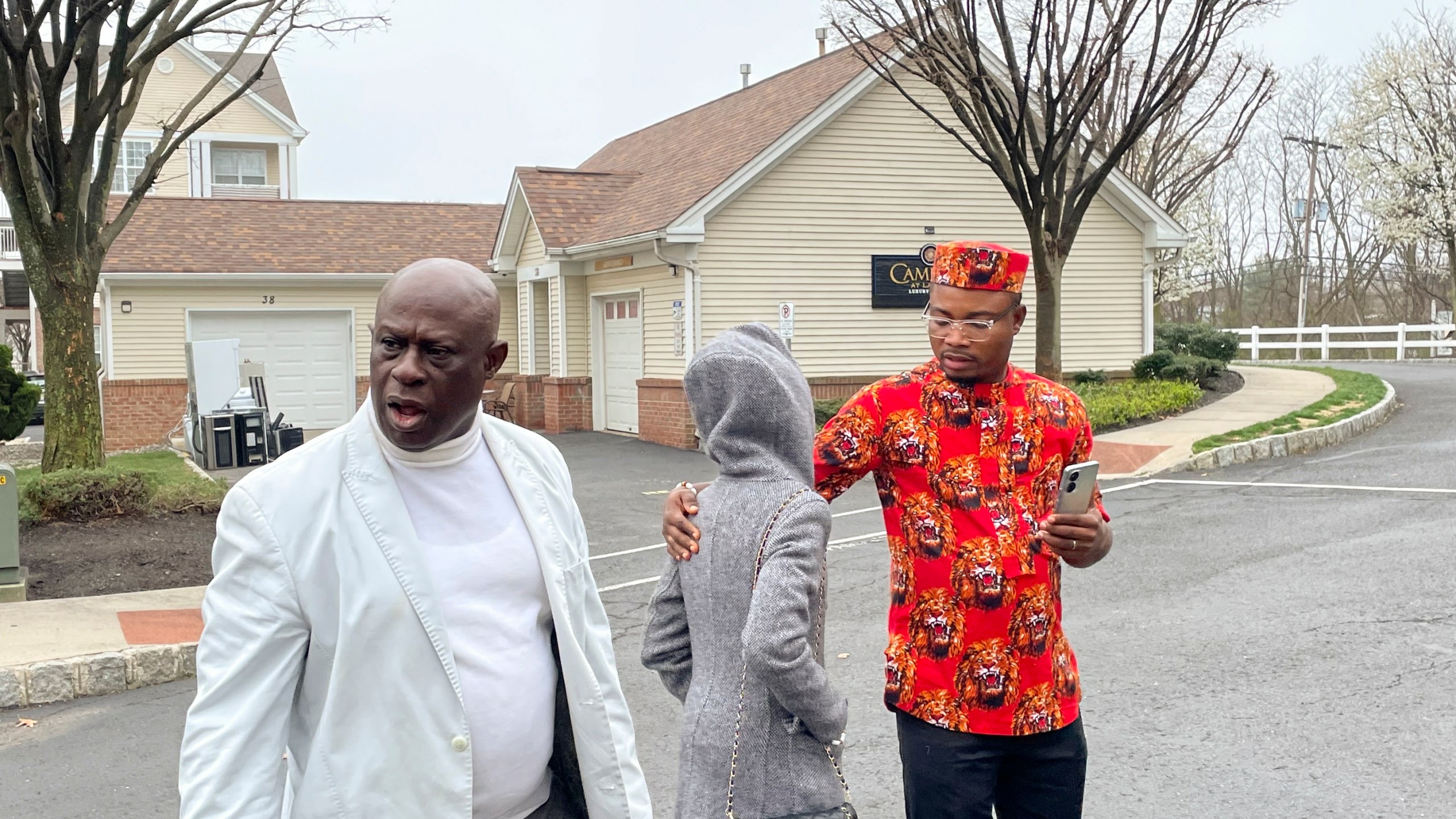 From left, Prince Dwumfour, Nicole Teliano and Peter Ezechukwu walk near the scene of the fatal shooting of their family member, Eunice Dwumfour, in Sayreville, N.J., April 5, 2023. Eunice Dwumfour, a Sayreville council member, was gunned down Feb. 1 as she arrived home in Sayreville. (AP Photo/Maryclaire Dale)