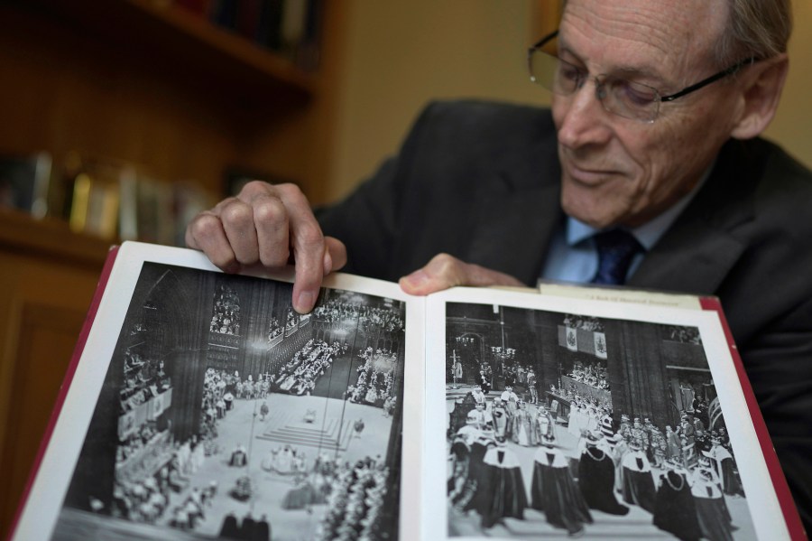 James Wilkinson points to where he was seated, as a young Westminster Abbey chorister, during the June 2, 1953 coronation of Queen Elizabeth II, in London, April 17, 2023. The choristers spent months preparing for the service, learning the music and lyrics to the hymns they would sing during the three-hour long ceremony. Wilkinson knew he was part of something extraordinary, so the future BBC journalist recorded everything he saw, in a looping script on the now-yellowed pages of his diary. (AP Photo/Kin Cheung)