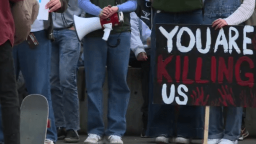 Oregon student holds "You are killing us" sign at climate rally