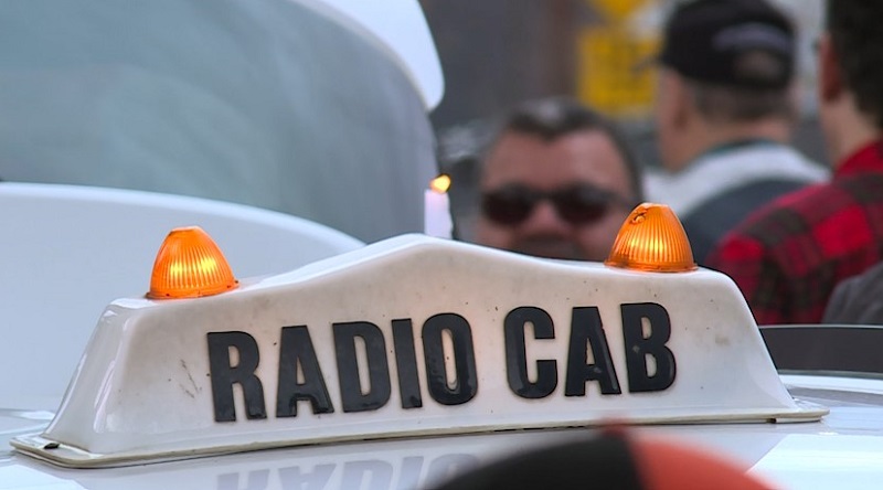 A candle flickers on a Radio Cab roof sign during the public memorial for Radio Cab driver Reese Lawhon, April 22, 2023 (KOIN)