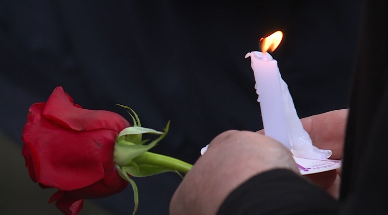 A candle and a flower are held by a person attending the public memorial for Radio Cab driver Reese Lawhon, April 22, 2023 (KOIN)