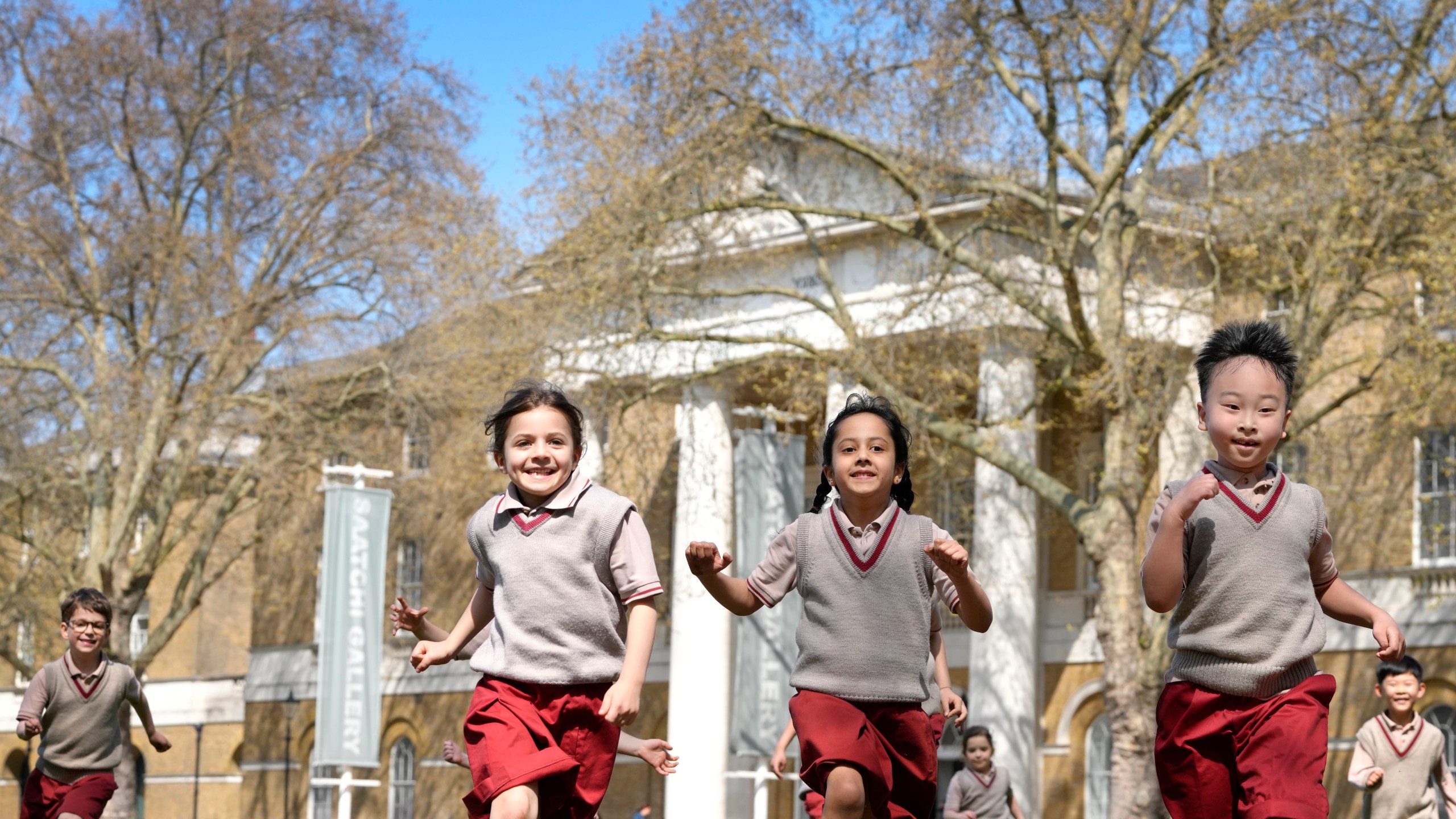 Pupils from Hill House School in London, play on the grass in front of the now Saatchi Gallery, where Britain's King Charles III played sport as a pupil, Thursday, April 20, 2023. King Charles III hasn’t even been crowned yet, but his name is already etched on the walls of Hill House School in London. A wooden slab just inside the front door records Nov. 7, 1956, as the day the future king enrolled at Hill House alongside other notable dates in the school’s 72-year history. (AP Photo/Kirsty Wigglesworth)