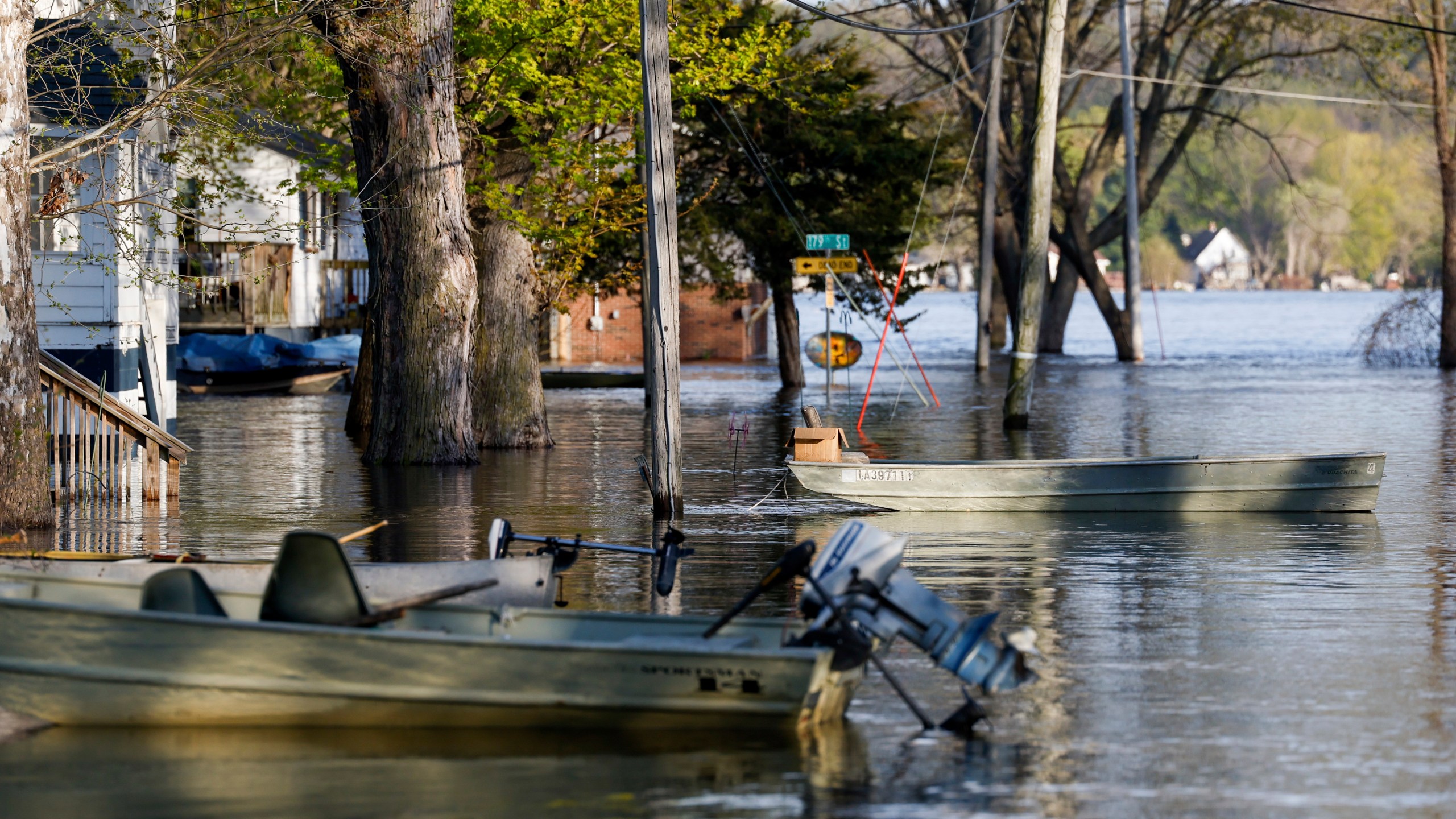 Boats float tethered in the front yards of homes along South Spencer Road as the Mississippi River continues to rise forcing residents to make alternative transportation between their homes and the rising water covering their street, Thursday, April 27, 2023, in Pleasant Valley, Iowa. (Nikos Frazier/Quad City Times via AP)