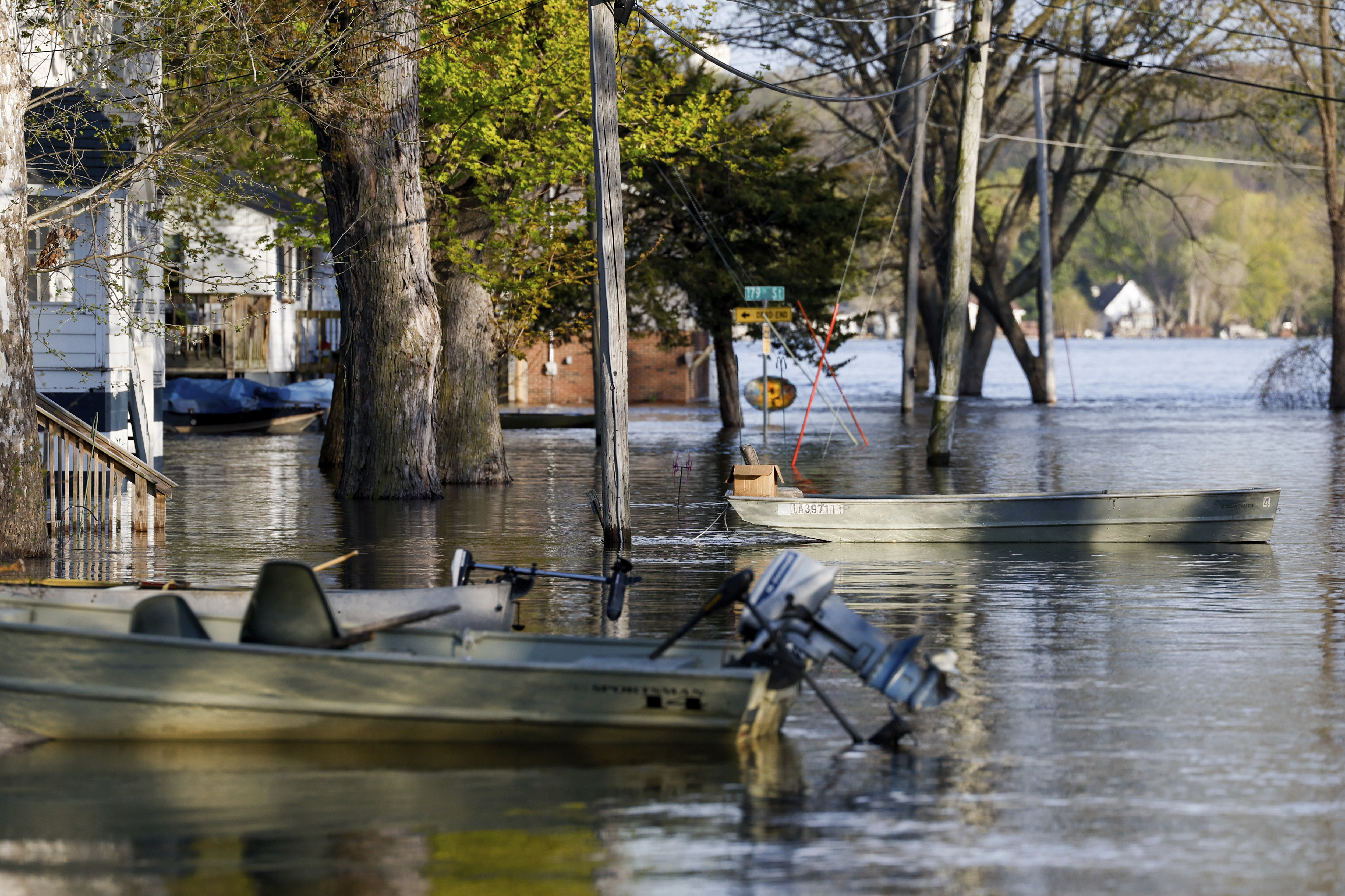 Boats float tethered in the front yards of homes along South Spencer Road as the Mississippi River continues to rise forcing residents to make alternative transportation between their homes and the rising water covering their street, Thursday, April 27, 2023, in Pleasant Valley, Iowa. (Nikos Frazier/Quad City Times via AP)