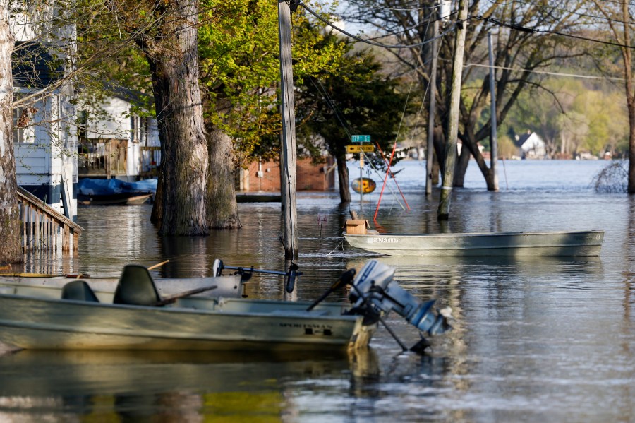 Boats float tethered in the front yards of homes along South Spencer Road as the Mississippi River continues to rise forcing residents to make alternative transportation between their homes and the rising water covering their street, Thursday, April 27, 2023, in Pleasant Valley, Iowa. (Nikos Frazier/Quad City Times via AP)