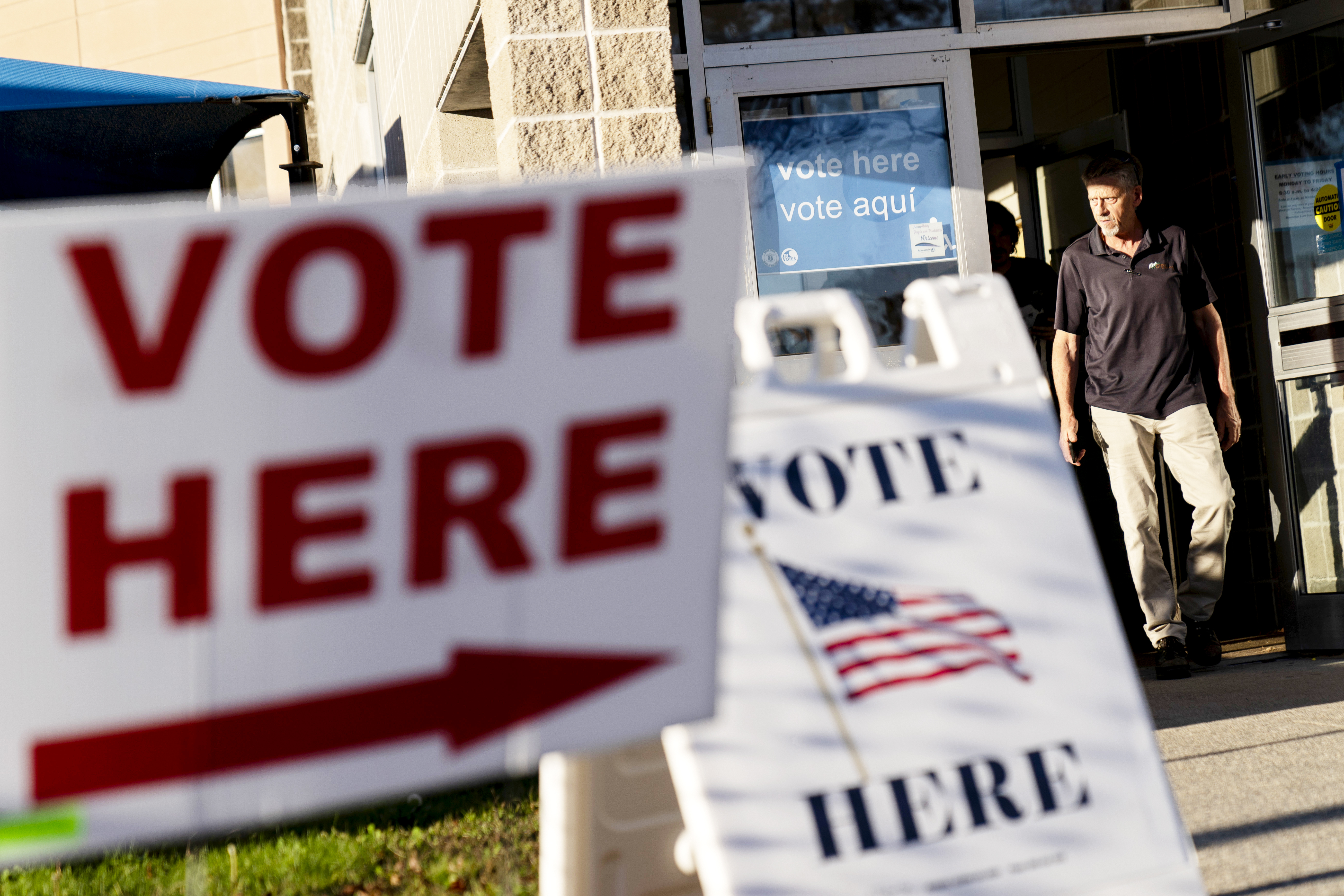 FILE - Signs point to the entrance on the last day of early voting before the midterm election as a man walks out of a polling site in Cranston, R.I., on Nov. 7, 2022. Almost half of all voters in the 2022 midterm elections cast their ballots before Election Day either by mail or through early voting, with Asian and Hispanic voters leading the way, new data from the U.S. Census Bureau released Tuesday, May 2, 2023, shows, even as Republican-led states have tightened rules on voting by mail. (AP Photo/David Goldman, File)