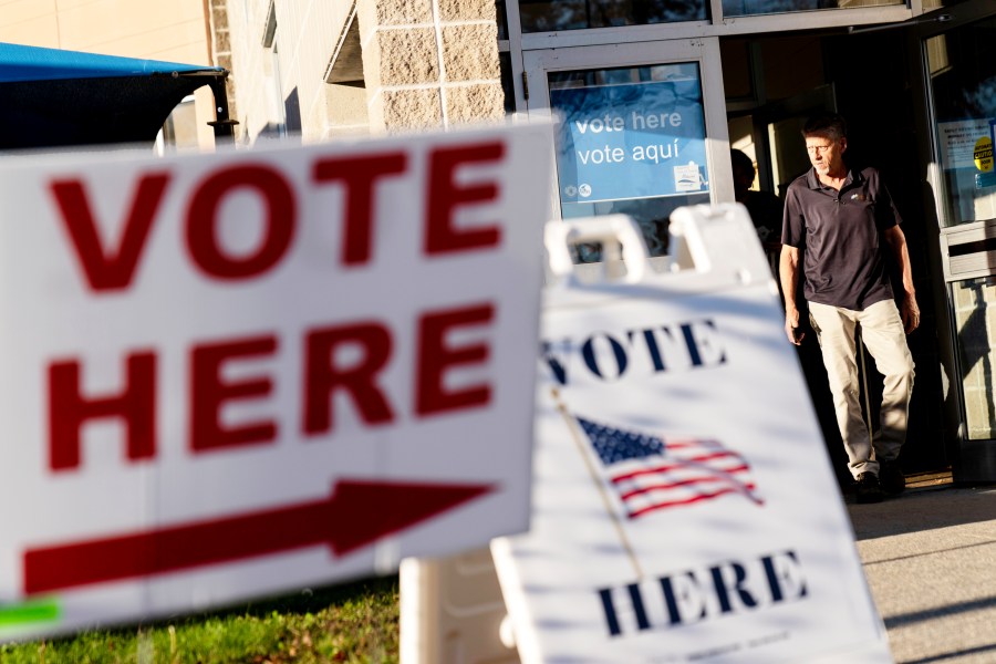 FILE - Signs point to the entrance on the last day of early voting before the midterm election as a man walks out of a polling site in Cranston, R.I., on Nov. 7, 2022. Almost half of all voters in the 2022 midterm elections cast their ballots before Election Day either by mail or through early voting, with Asian and Hispanic voters leading the way, new data from the U.S. Census Bureau released Tuesday, May 2, 2023, shows, even as Republican-led states have tightened rules on voting by mail. (AP Photo/David Goldman, File)