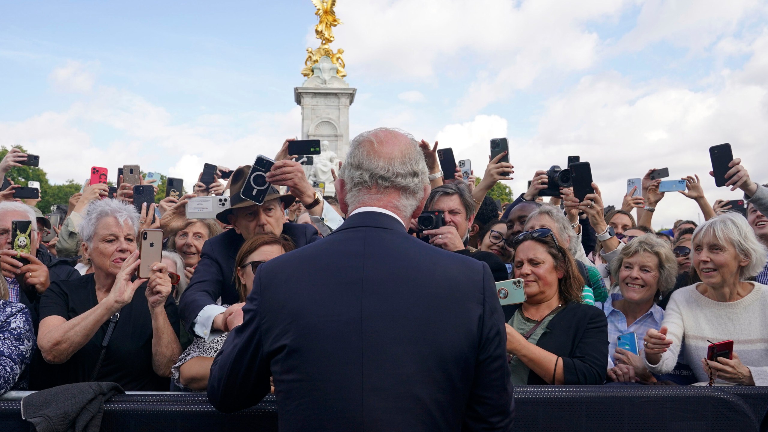 FILE - Britain's King Charles III, back to camera, greets well-wishers as he walks by the gates of Buckingham Palace following Thursday's death of Queen Elizabeth II, in London, Friday, Sept. 9, 2022. King Charles III will be crowned Saturday, May 6, 2023 at Westminster Abbey in an event full of all the pageantry Britain can muster. (Yui Mok/Pool Photo via AP, File)