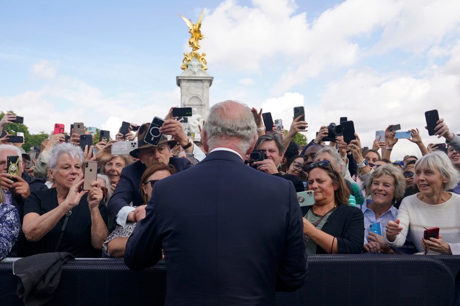 FILE - Britain's King Charles III, back to camera, greets well-wishers as he walks by the gates of Buckingham Palace following Thursday's death of Queen Elizabeth II, in London, Friday, Sept. 9, 2022. King Charles III will be crowned Saturday, May 6, 2023 at Westminster Abbey in an event full of all the pageantry Britain can muster. (Yui Mok/Pool Photo via AP, File)