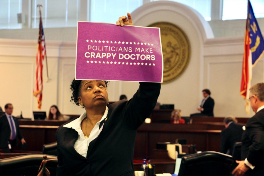 North Carolina state Sen. Kandie Smith, a Pitt County Democrat, holds up a sign that reads "Politicians Make Crappy Doctors" on the Senate floor in Raleigh, N.C., after the chamber voted to approve new abortion restrictions, Thursday, May 4, 2023. (AP Photo/Hannah Schoenbaum)