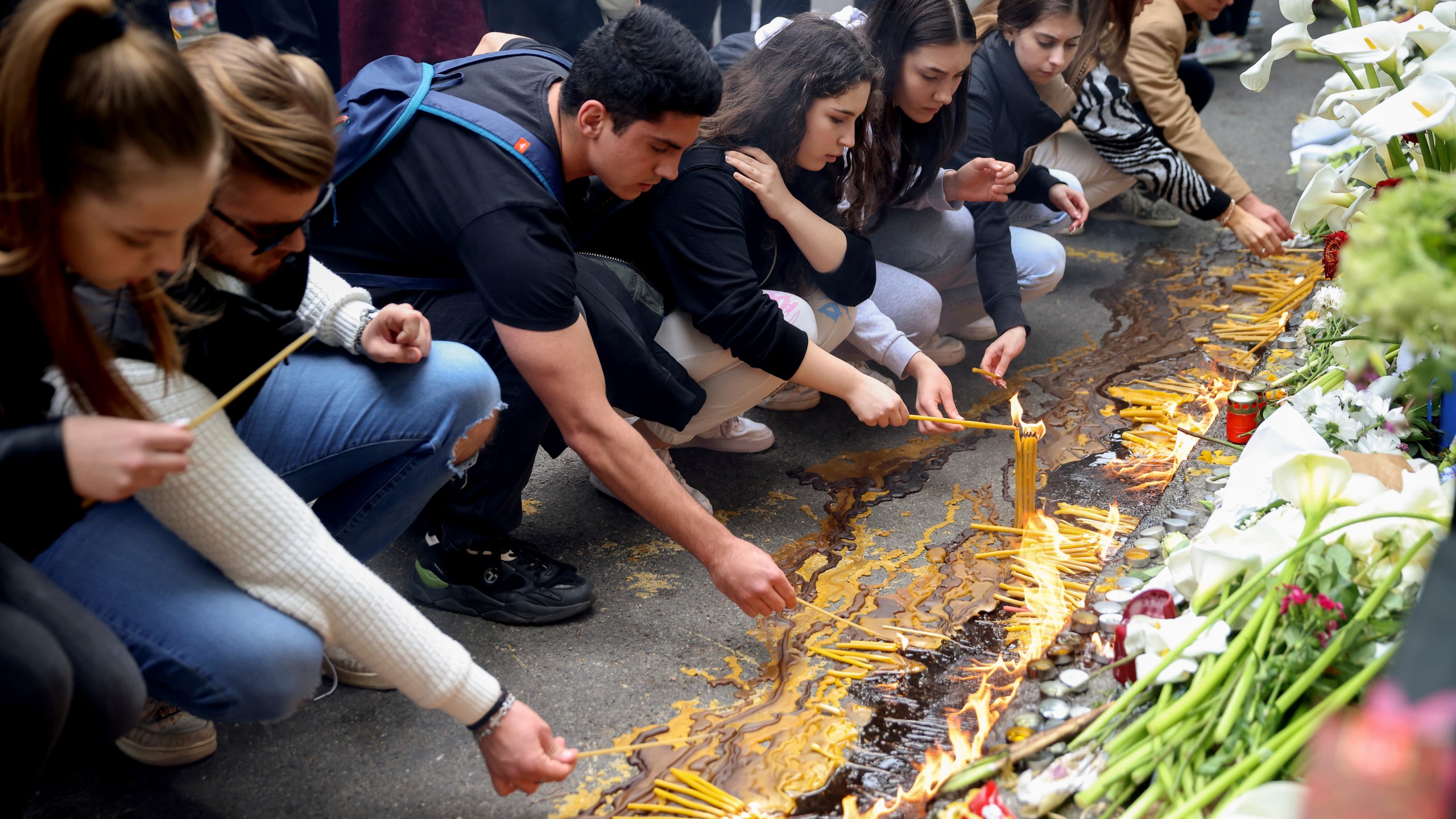 School children light candles near the Vladislav Ribnikar school in Belgrade, Serbia, Thursday, May 4, 2023. Many wearing black and carrying flowers, scores of Serbian students on Thursday paid silent homage to their peers killed a day earlier when a 13-year-old boy used his father’s guns in a school shooting rampage that sent shock waves through the nation and triggered moves to boost gun control. (AP Photo/Armin Durgut)