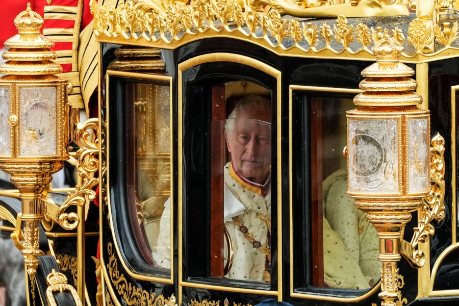 Britain's King Charles III is seen through the window of the Diamond Jubilee State Coach as he leaves Buckingham Palace with Camilla, the Queen Consort, for the coronation ceremony in London, Saturday, May 6, 2023. (AP Photo/Frank Augstein)