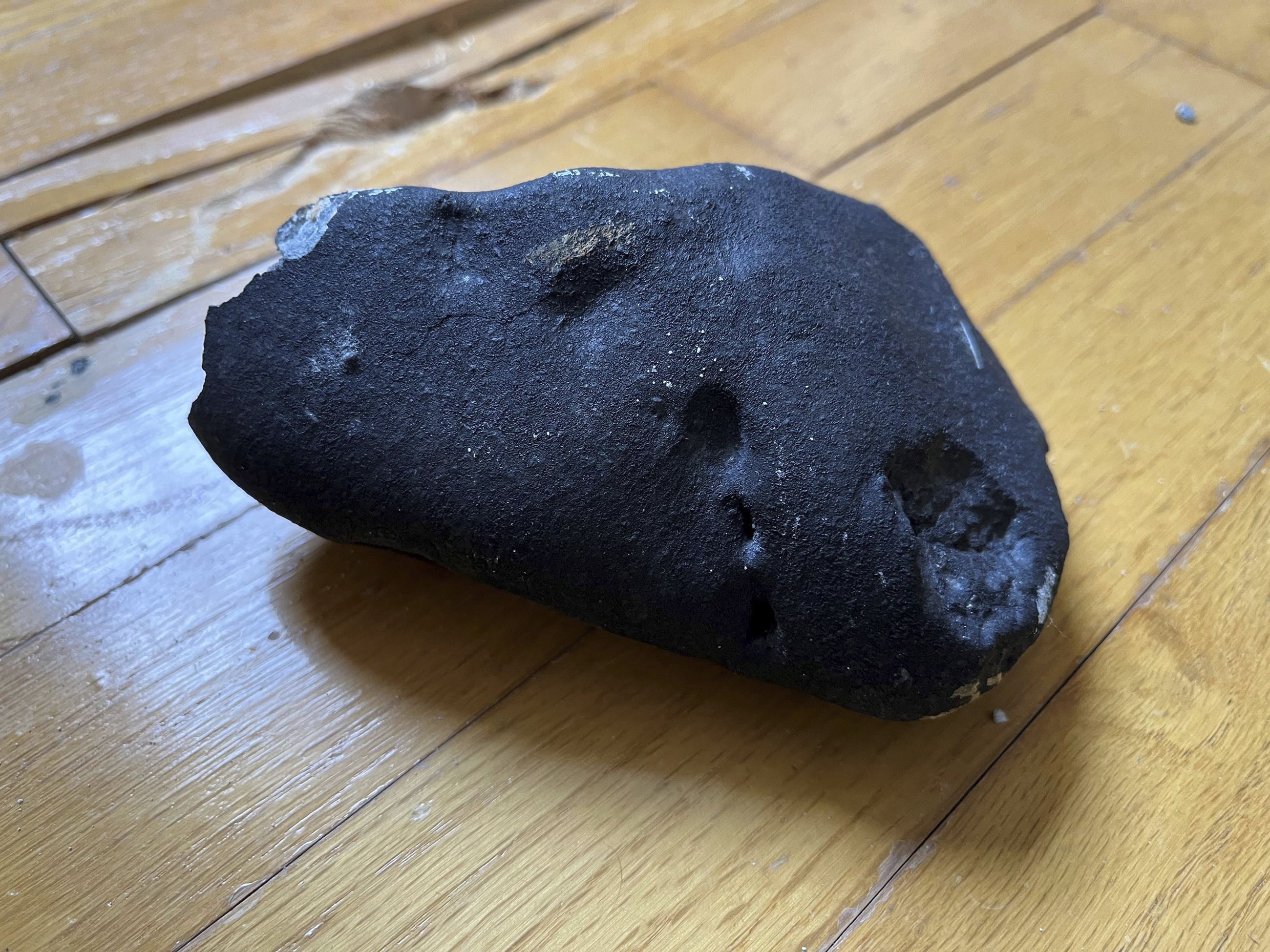 This image provided by Hopewell Township Police Department shows a metallic object believed to be a meteorite that struck the roof a residence in Hopewell Township, N.J. Hopewell Township police said the 4- by-6-inch, oblong-shaped object struck the ranch-style home on Monday, May 8, 2023 and eventually came to rest on a floor. It's estimated to weigh about four pounds. (Hopewell Township Police Department via AP)